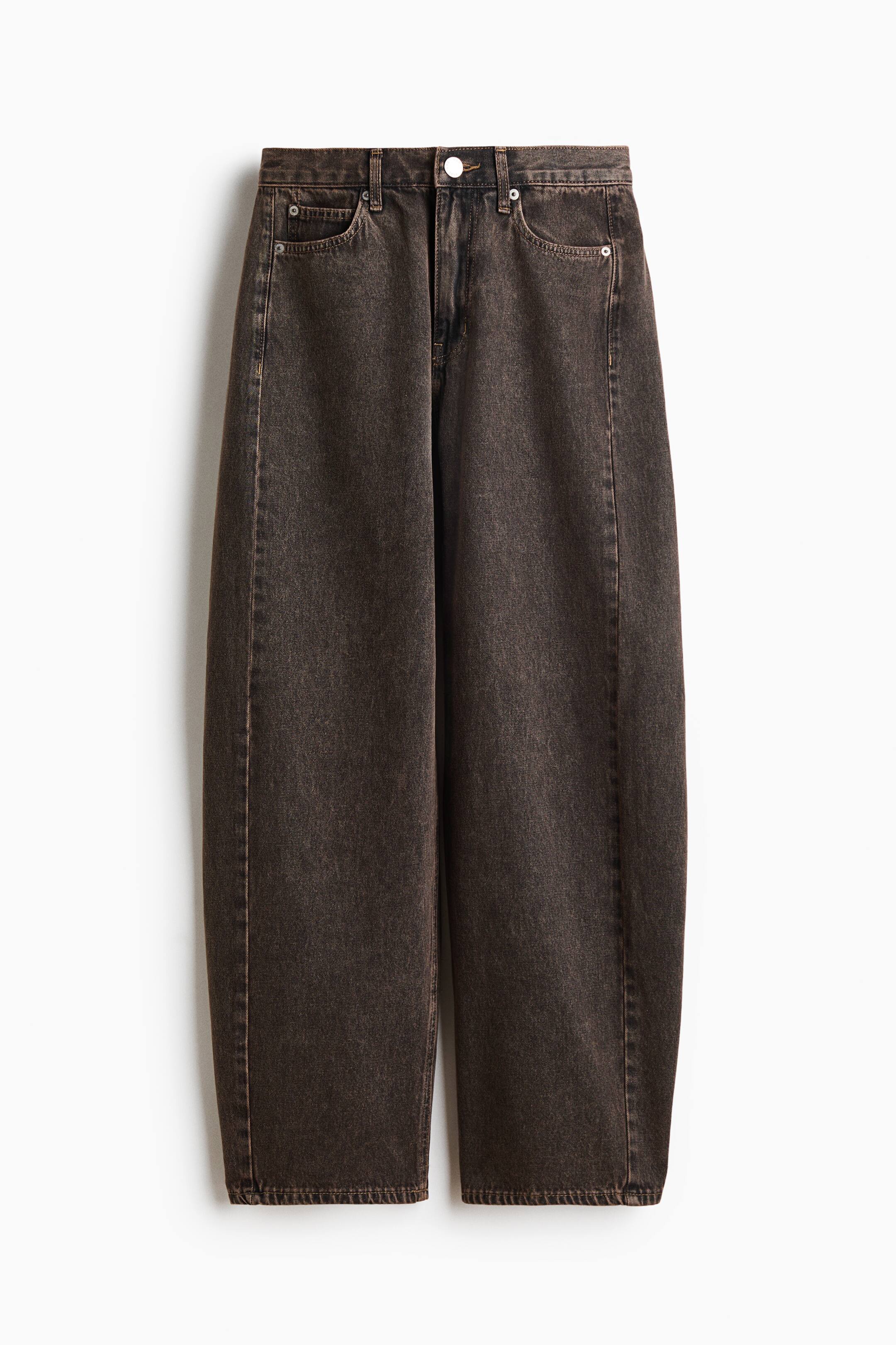 Xem ảnh lớn hơn: Một chiếc quần jeans denim màu nâu đậm, đã wash, được chụp từ phía trước, với phần ống quần cong, phồng nhẹ và thu hẹp dần về phía gấu. Quần jeans nổi bật với kiểu dáng 5 túi cổ điển, cạp vừa, đai thắt lưng và cúc cài trung tâm.