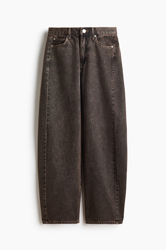 Une paire de jeans en denim délavé marron foncé est présentée de face, avec des jambes courbes et volumineuses qui se resserrent légèrement vers les ourlets. Ce jean met en avant un style classique à cinq poches avec une taille standard, des passants de ceinture et une fermeture centrale par bouton. - 1
