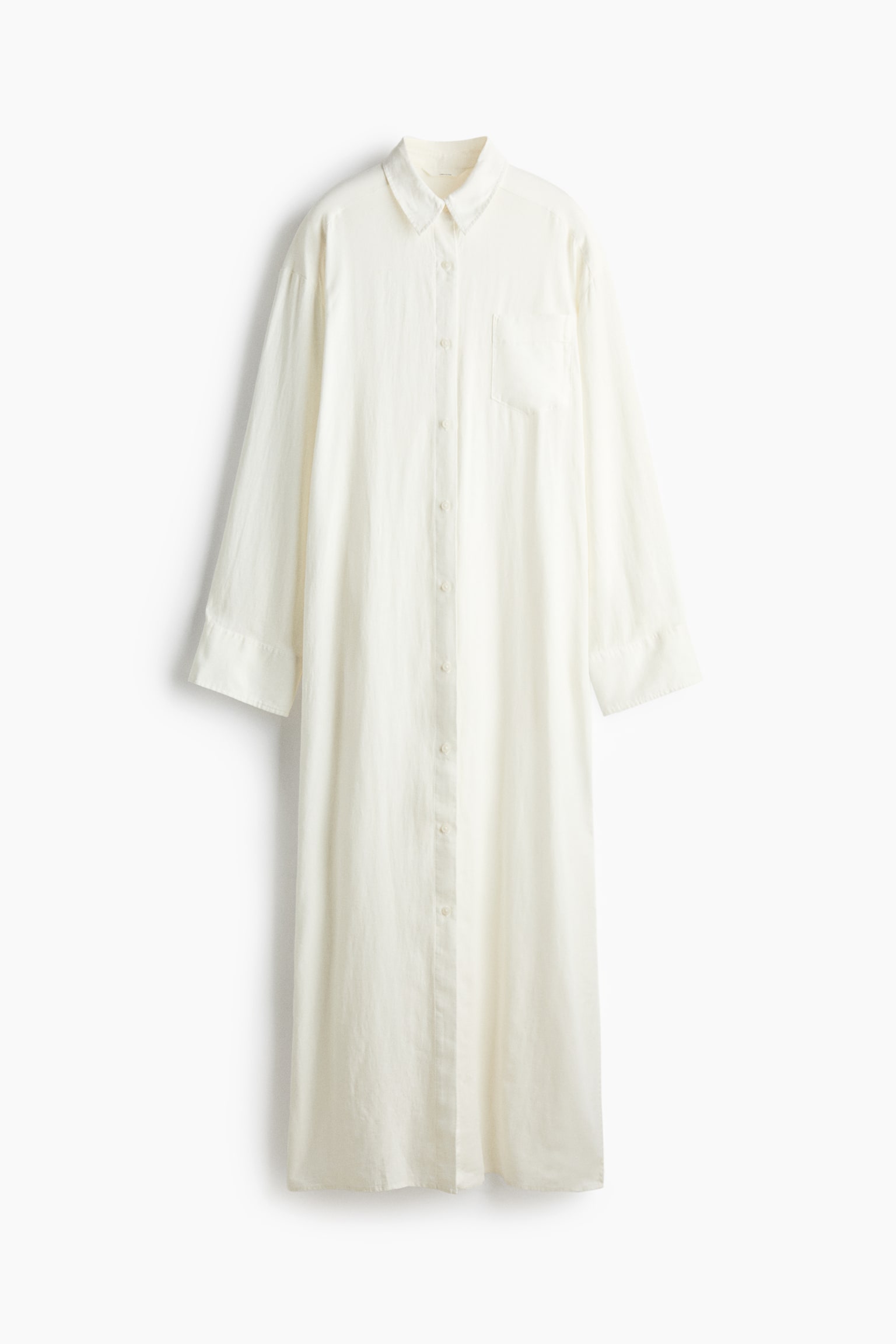 Ein cremefarbenes Maxi-Hemdkleid ist von vorne zu sehen und verfÃ¼gt Ã¼ber einen spitzen Kragen, eine durchgehende Knopfleiste vorn sowie eine einzelne offene Brusttasche. Das Kleid ist mit langen Ãrmeln mit breiten Manschetten und einer lockeren, gerade geschnittenen Silhouette gestaltet.
