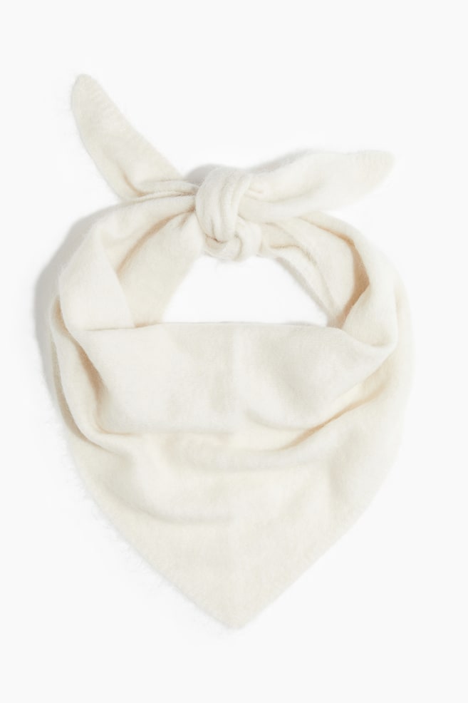Un bandana blanc cassé est noué avec un nœud en haut, et son tissu doux et légèrement duveteux forme une forme triangulaire en dessous du nœud. - 1