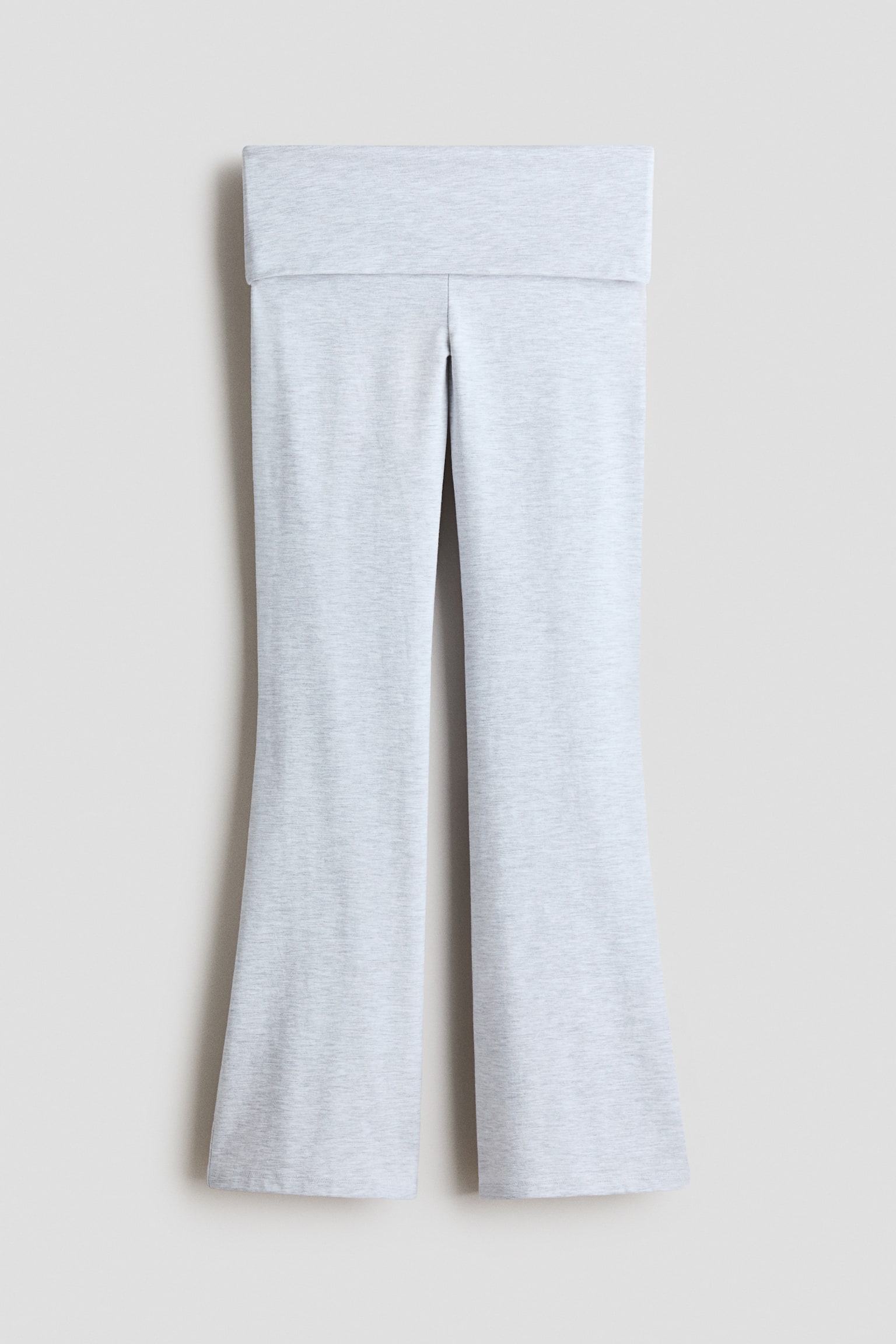 Hellgraue Flared-Hose mit Melange-Effekt hängen in einer frontalen Ansicht und verfügen über einen breiten, umklappbaren Bund sowie Beine, die zum Saum hin allmählich ausgestellt verlaufen. Der weiche Jersey-Strickstoff zeigt eine dezente melierte Textur.