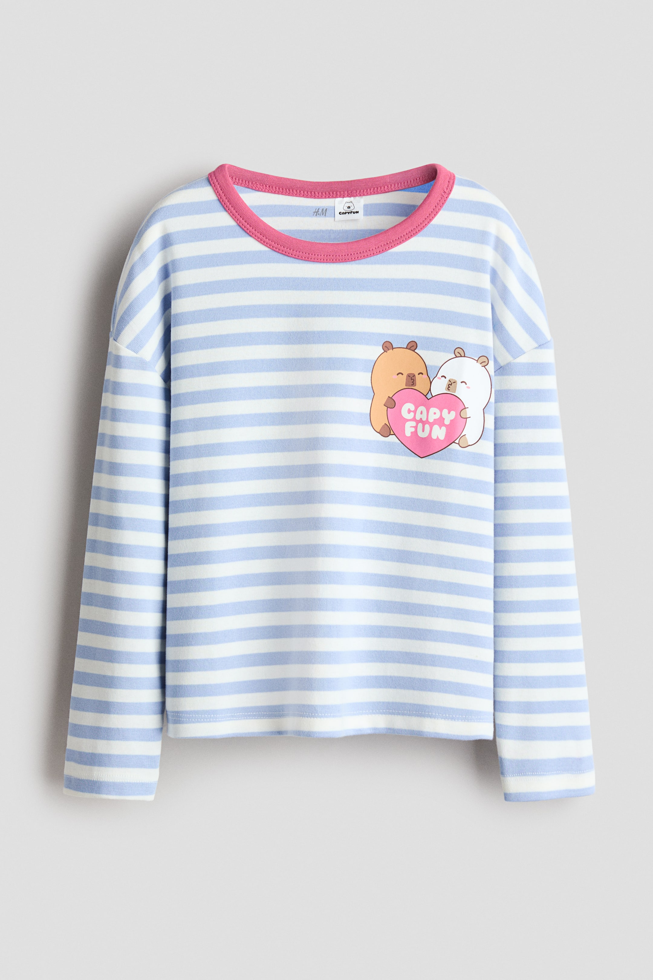 Agrandir l'image: Un t-shirt à manches longues arbore des rayures horizontales bleu clair et blanches, avec un col rond bordé de rose et des épaules tombantes. Un motif brodé apparaît sur le devant, représentant deux animaux de dessin animé tenant un cœur rose avec le texte 'CAPY FUN'.