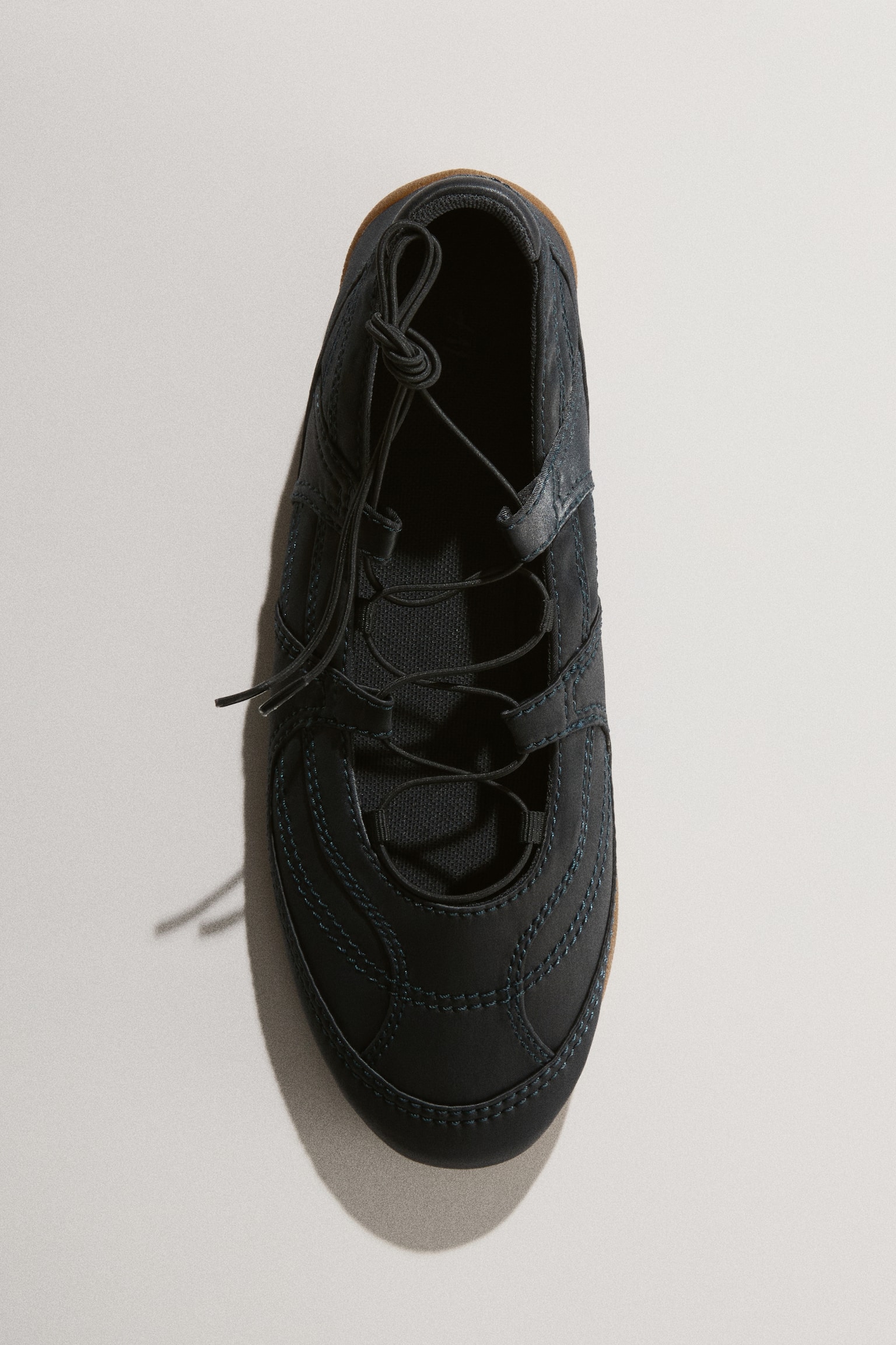 A pair of dark blue casual shoes is displayed from a top-down perspective, facing forward. Each shoe showcases a stitched upper with elastic laces tied in a knot at the top, and a slim brown sole edge is visible. - 1