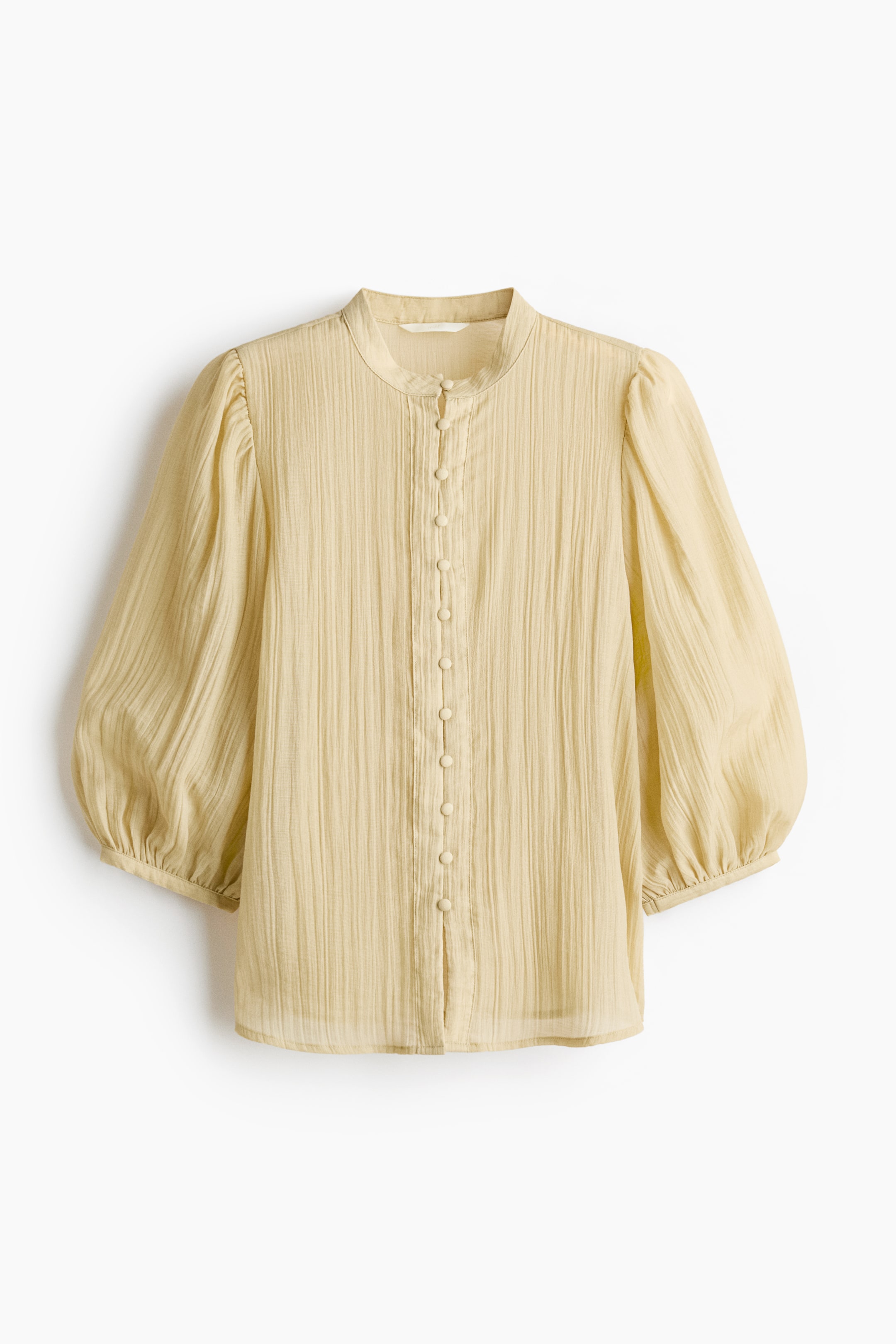 Xem ảnh lớn hơn: Áo blouse màu vàng nhạt, MẶT TRƯỚC, có cổ áo kiểu băng và hàng nút đầy đủ với các nút cùng màu. Tay áo phồng, xếp nếp kéo dài đến khuỷu tay và một kết cấu nhăn nhẹ có thể nhìn thấy trên toàn bộ vải.