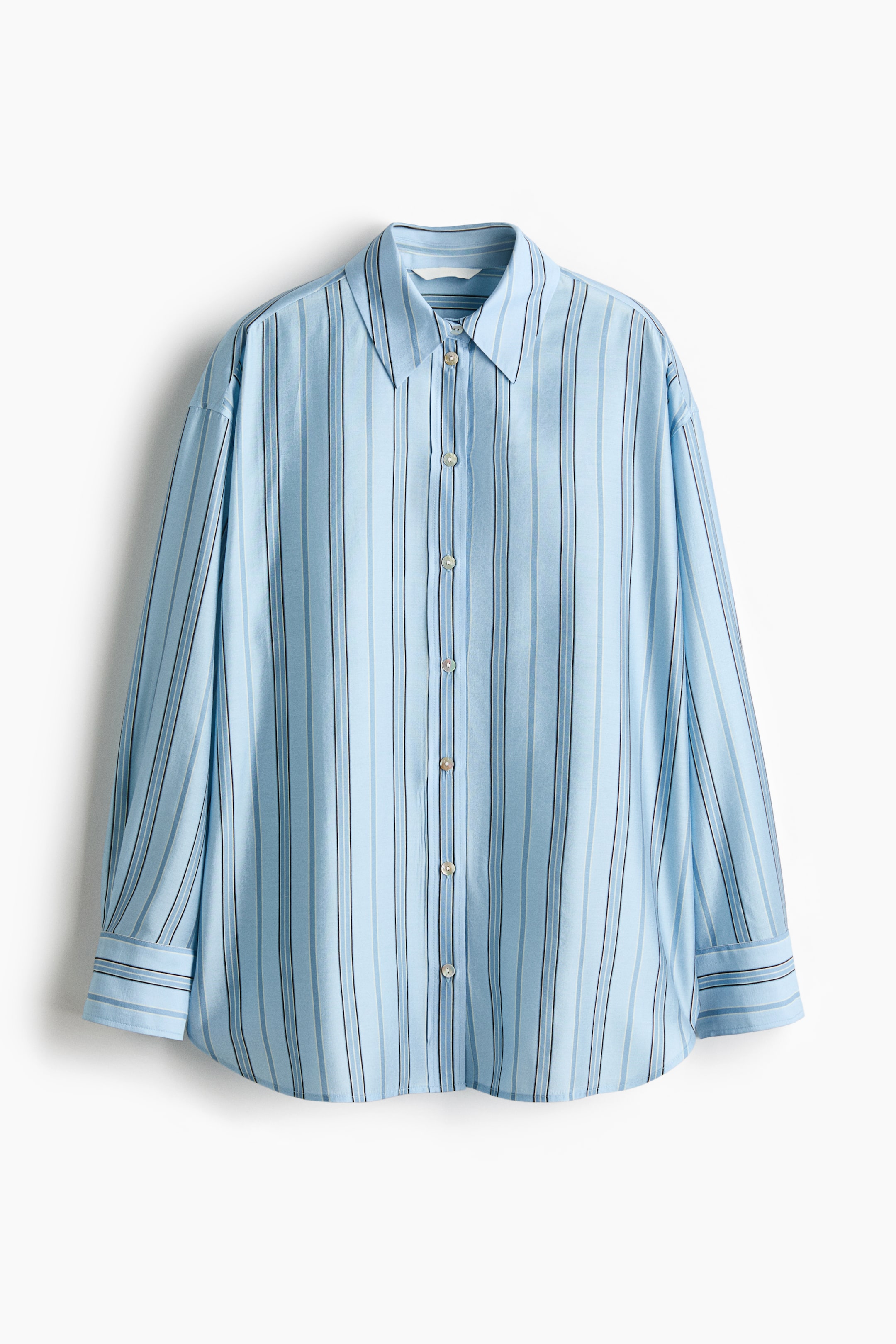 View larger image: An oversized light blue woven shirt is presenting its front, featuring vertical stripes in varying shades of blue and black. It is showcasing a collar, buttons running down the front, dropped shoulders, long sleeves with buttoned cuffs, and a rounded hem.