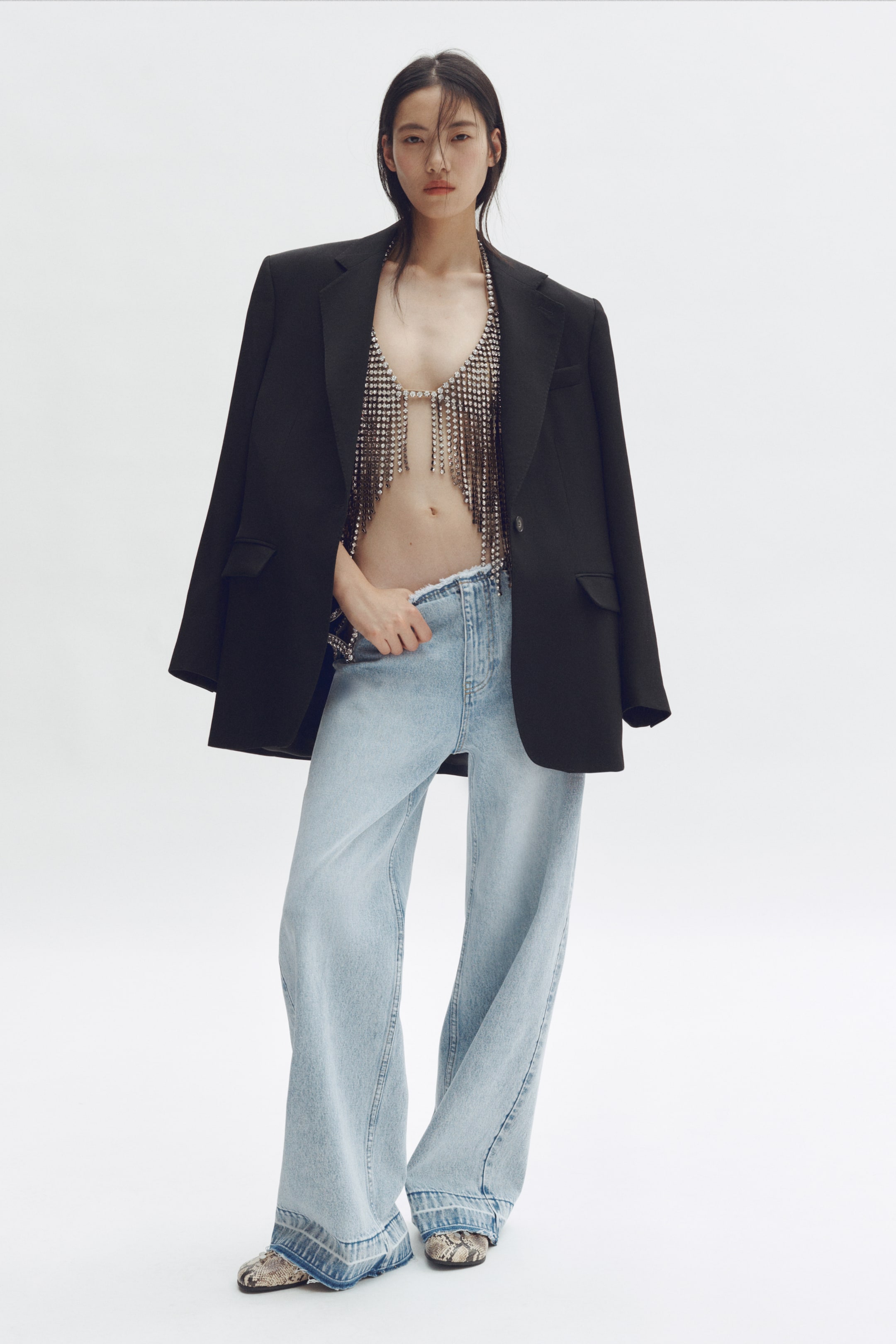 View larger image: "A black blazer featuring notch lapels and two flap pockets, styled draped over the shoulders."
