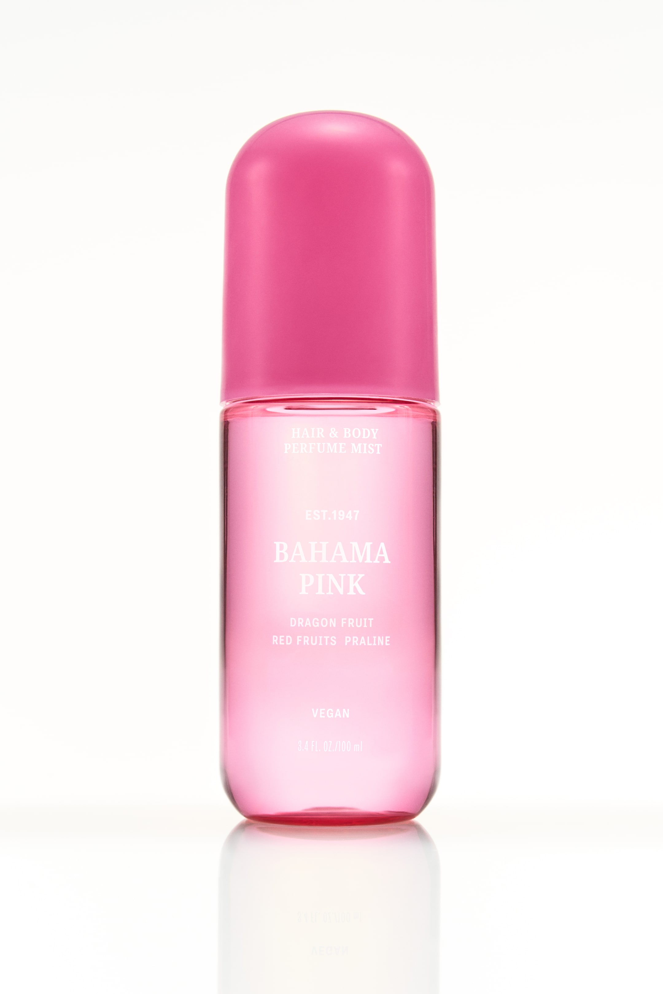 Ver imagem maior: Uma garrafa cilíndrica transparente de cor rosa de névoa de perfume para cabelo e corpo está em pé, com uma tampa arredondada de cor rosa vibrante. O texto em branco rotula a garrafa com 'Bahama Pink' e lista 'Fruta do Dragão' e 'Praliné de Frutos Vermelhos' como notas de fragrância.