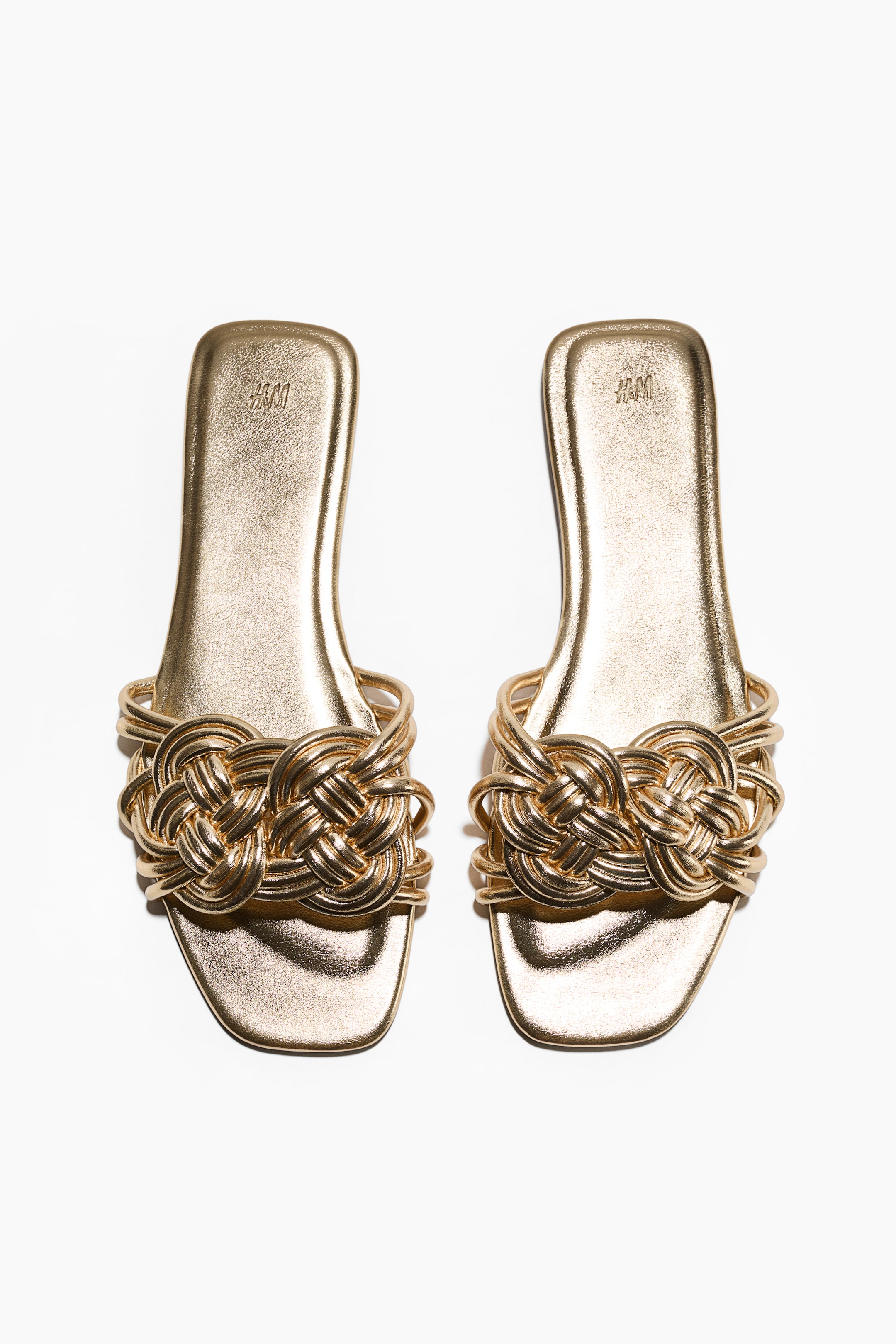 View larger image: Two gold sandals are showcased from the front, boasting wide foot straps crafted from intertwined narrow cords. The insoles appear lightly padded.