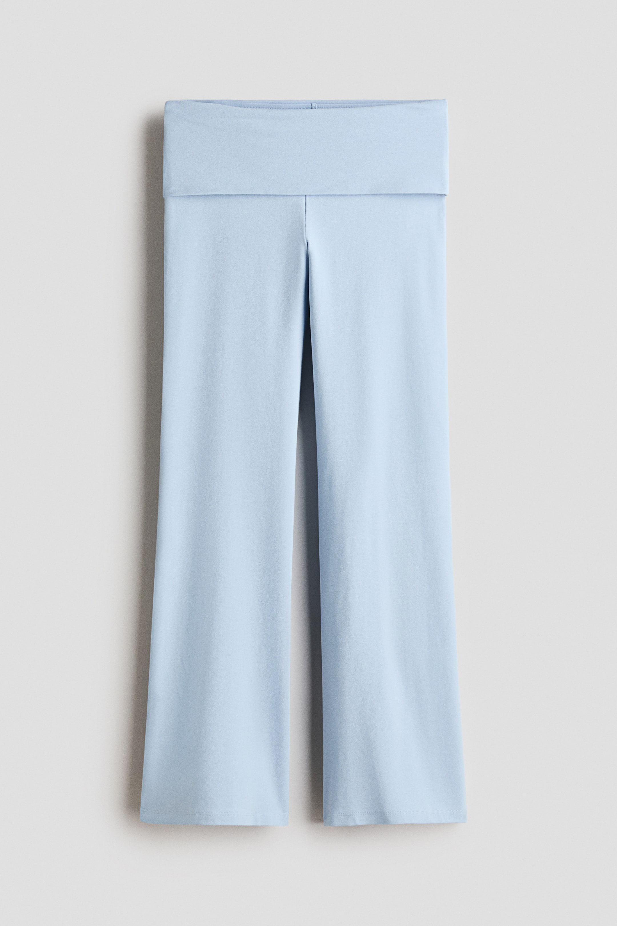 Visualizza immagine più grande: Un paio di pantaloni in maglia azzurri è appeso disteso, mettendo in risalto un ampio girovita ripiegato e una silhouette rilassata a gamba dritta. La vista frontale evidenzia il tessuto liscio in tinta unita e gli orli rifiniti con cura.