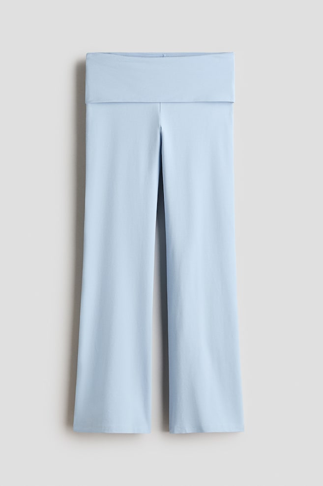 A pair of light blue knit pants is hanging flat, showcasing a wide fold-over waistband and a relaxed, straight-leg silhouette. The front-facing view highlights the smooth, solid-colored fabric and clean-finished hems. - 1