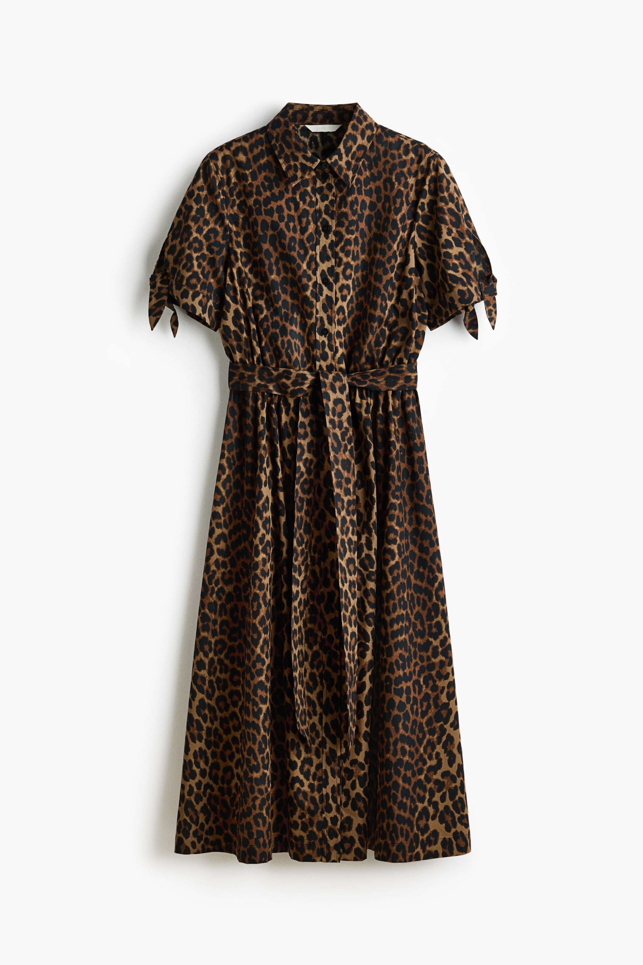 Näytä suurempi kuva: Edestäpäin katsottuna leopardikuvioinen paitamekko esittelee terävän kauluksen ja täyden nappikiinnityksen edessä. Se on varustettu lyhyillä hihoilla, joissa on solmimisdetaljit, ja mekkoon kuuluva yhteensopiva kangassolmio kiristää vyötäröä, minkä ansiosta mekko laskeutuu midi-mittaan.