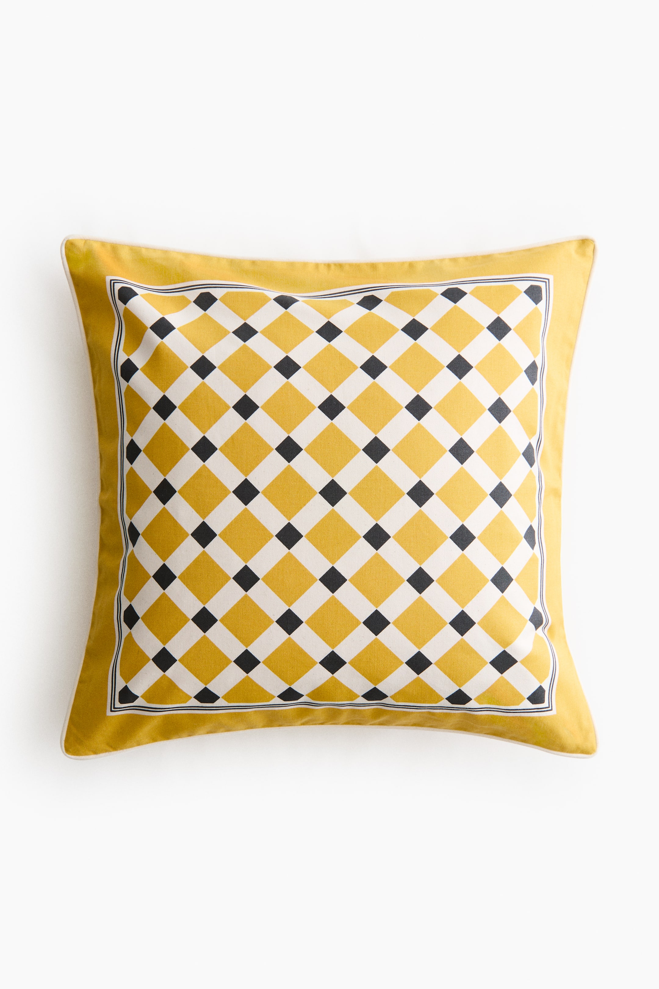 Voir une image plus grande: Un coussin carré est présenté de face, présentant un motif géométrique central composé de losanges jaunes, blancs et noirs. Ce motif est encadré d'une bordure jaune unie, et un passepoil blanc est visible le long du bord extérieur du coussin.