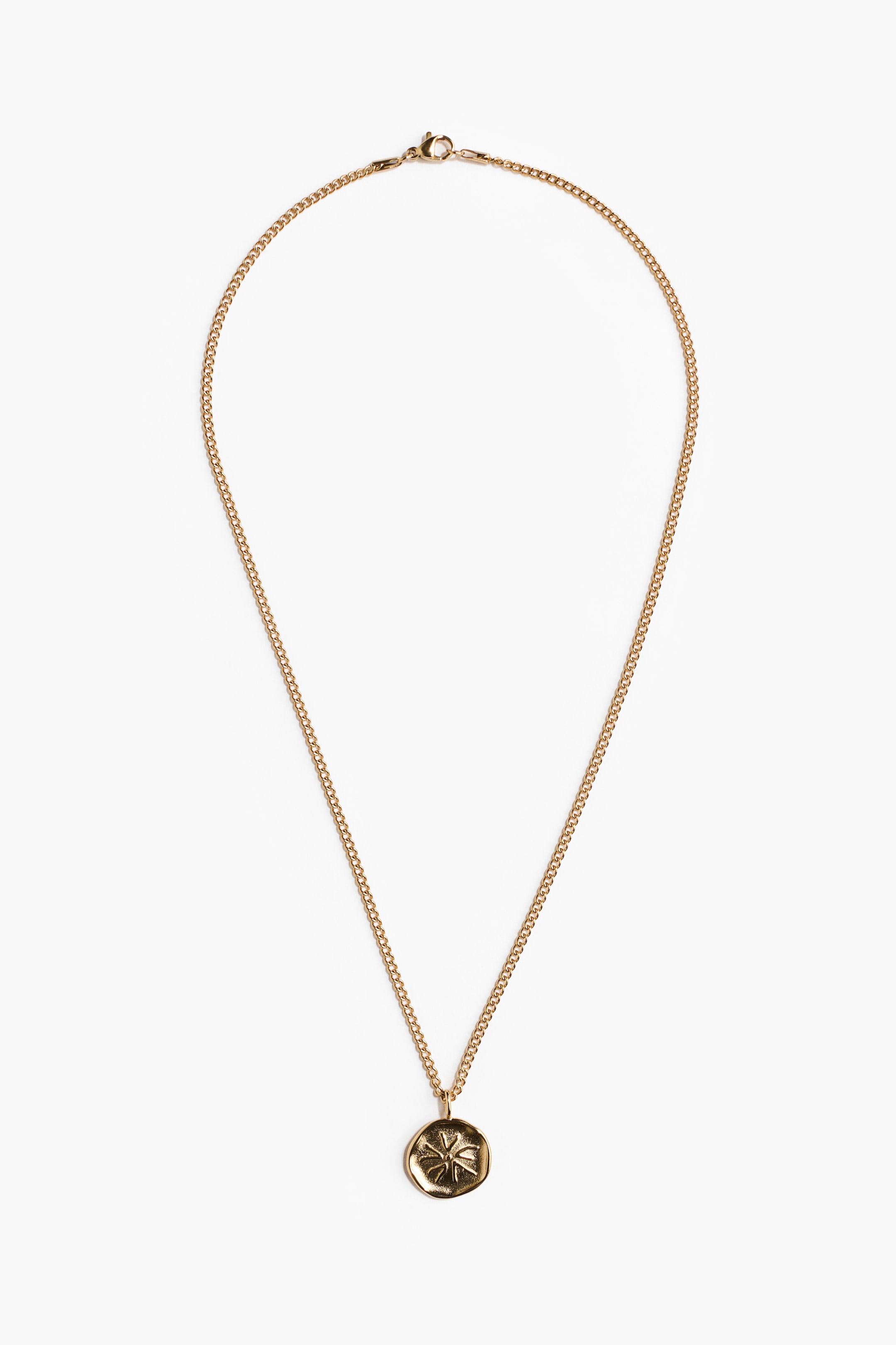 View larger image: A gold-toned necklace featuring a fine curb chain and a circular pendant, displayed lying flat in a V-shape. The chain is secured with a lobster clasp, and the pendant showcases a textured, irregular surface with a raised, abstract four-point design.