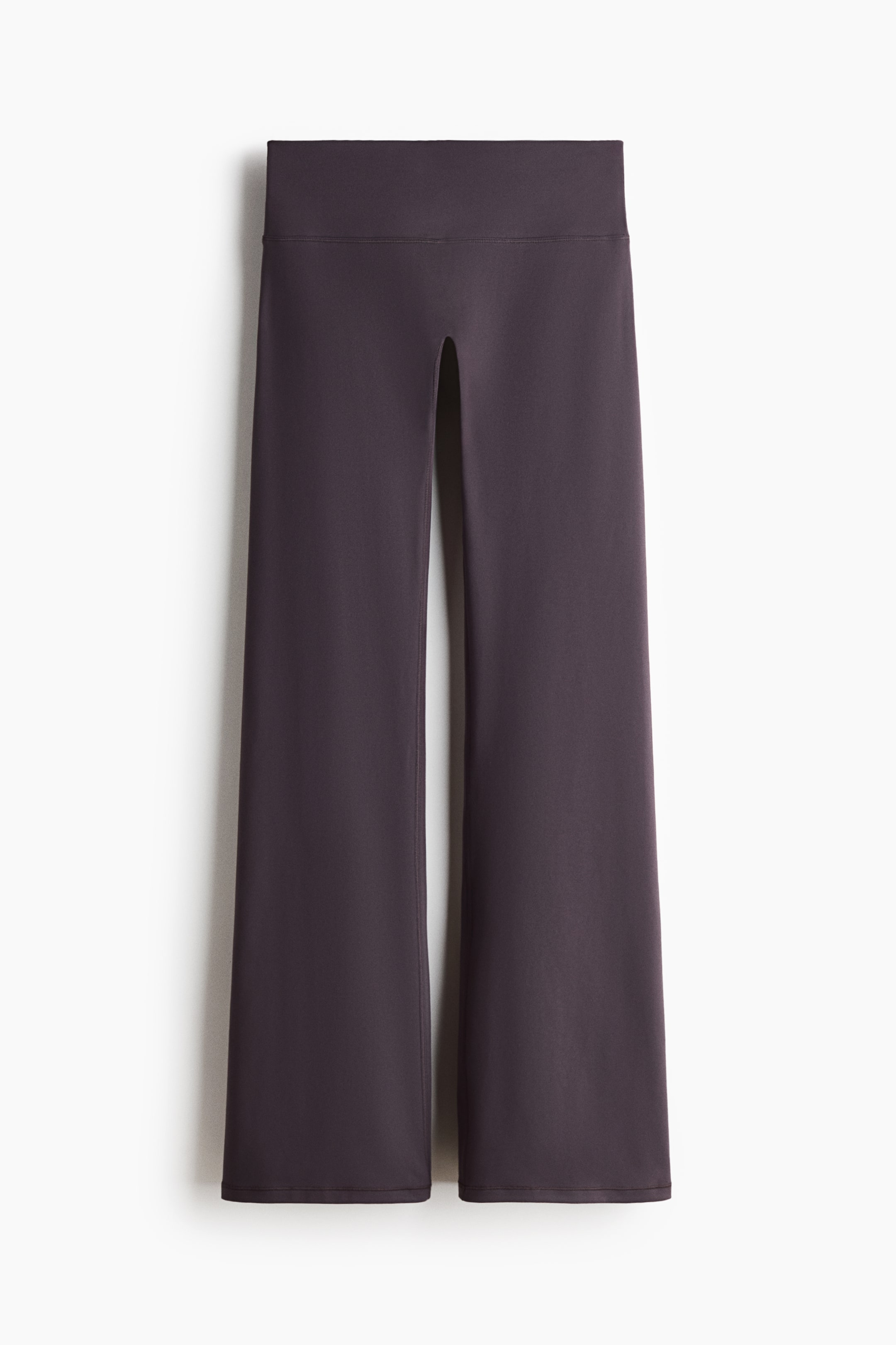 View larger image: A pair of dark grey low-rise flared sports leggings is laid flat, seen from the front. It features a wide, flat waistband and legs that flare from the thigh to the hem.