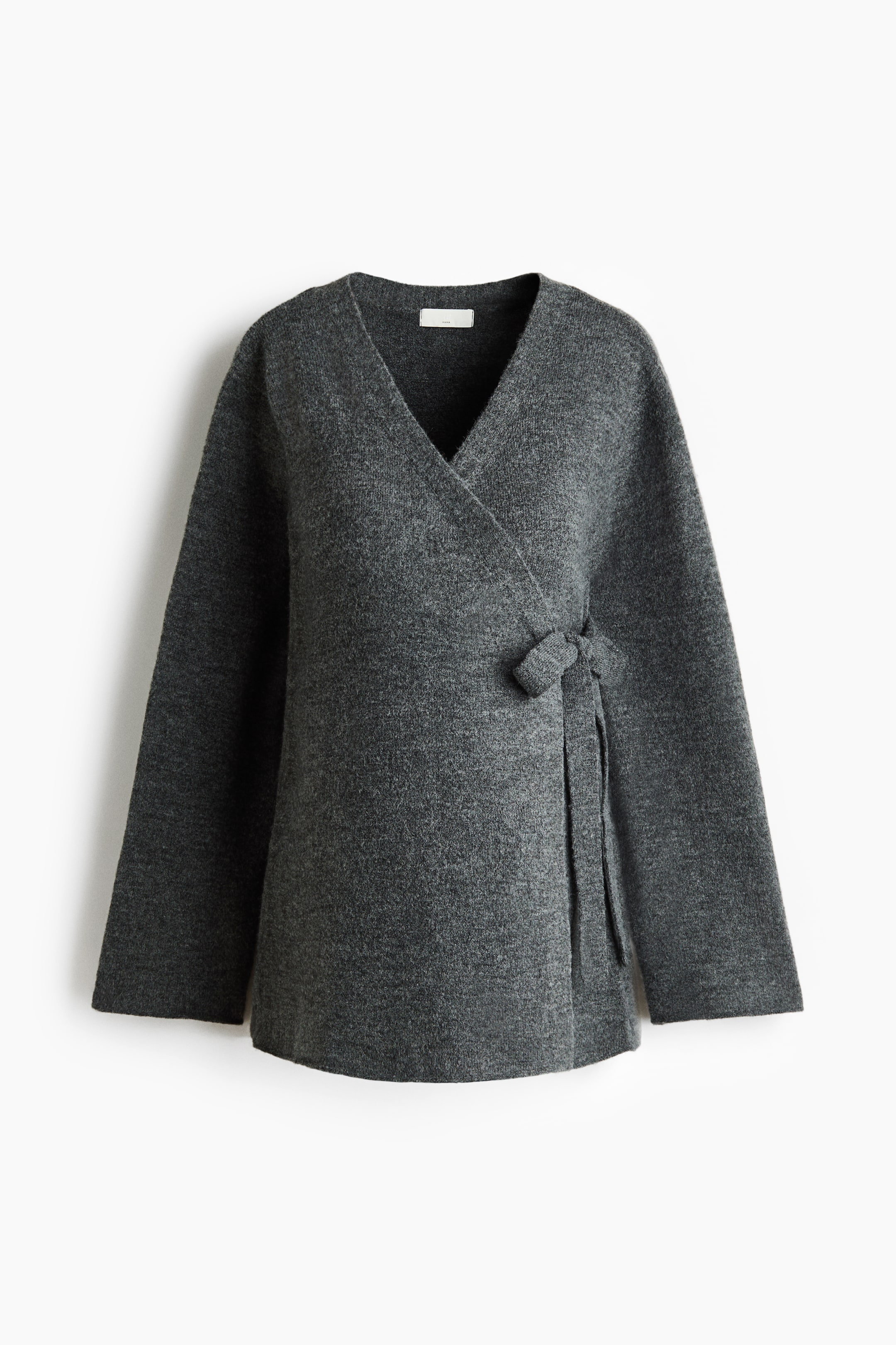 Visualizza l'immagine ingrandita: Un cardigan in maglia grigio scuro è mostrato frontalmente, con una chiusura a portafoglio sul davanti e lacci ben visibili annodati sul lato destro. È caratterizzato da spalle scese, maniche lunghe e polsini e orlo a costine.