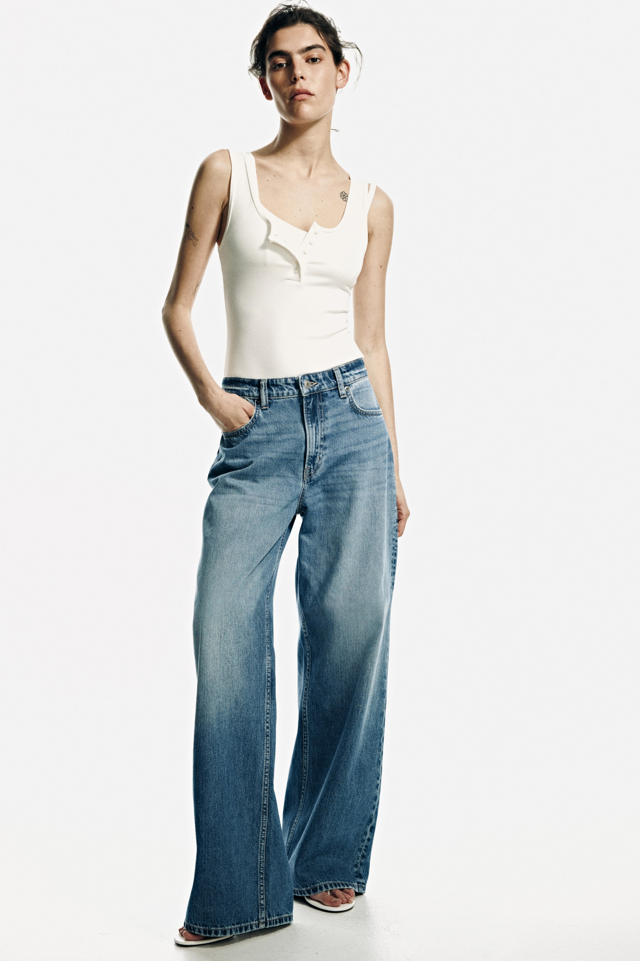 View larger image: These jeans showcase a medium blue wash with lighter fading on the thighs, offering a relaxed, wide-leg fit. They feature a high-waisted design, complete with front pockets and visible stitching, as seen from a front-facing perspective.