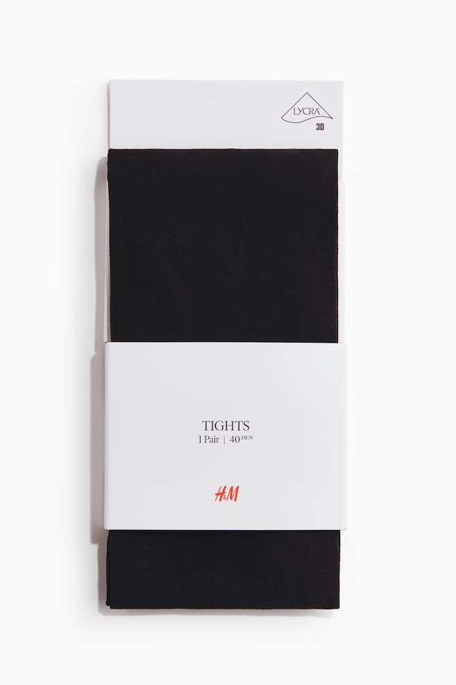 Black tights are presented folded inside a white retail packaging sleeve, facing forward. The packaging displays "LYCRA 3D" at the top, and "TIGHTS", "1 Pair \| 40 DEN", along with the "H&M" logo in the centre. - 1