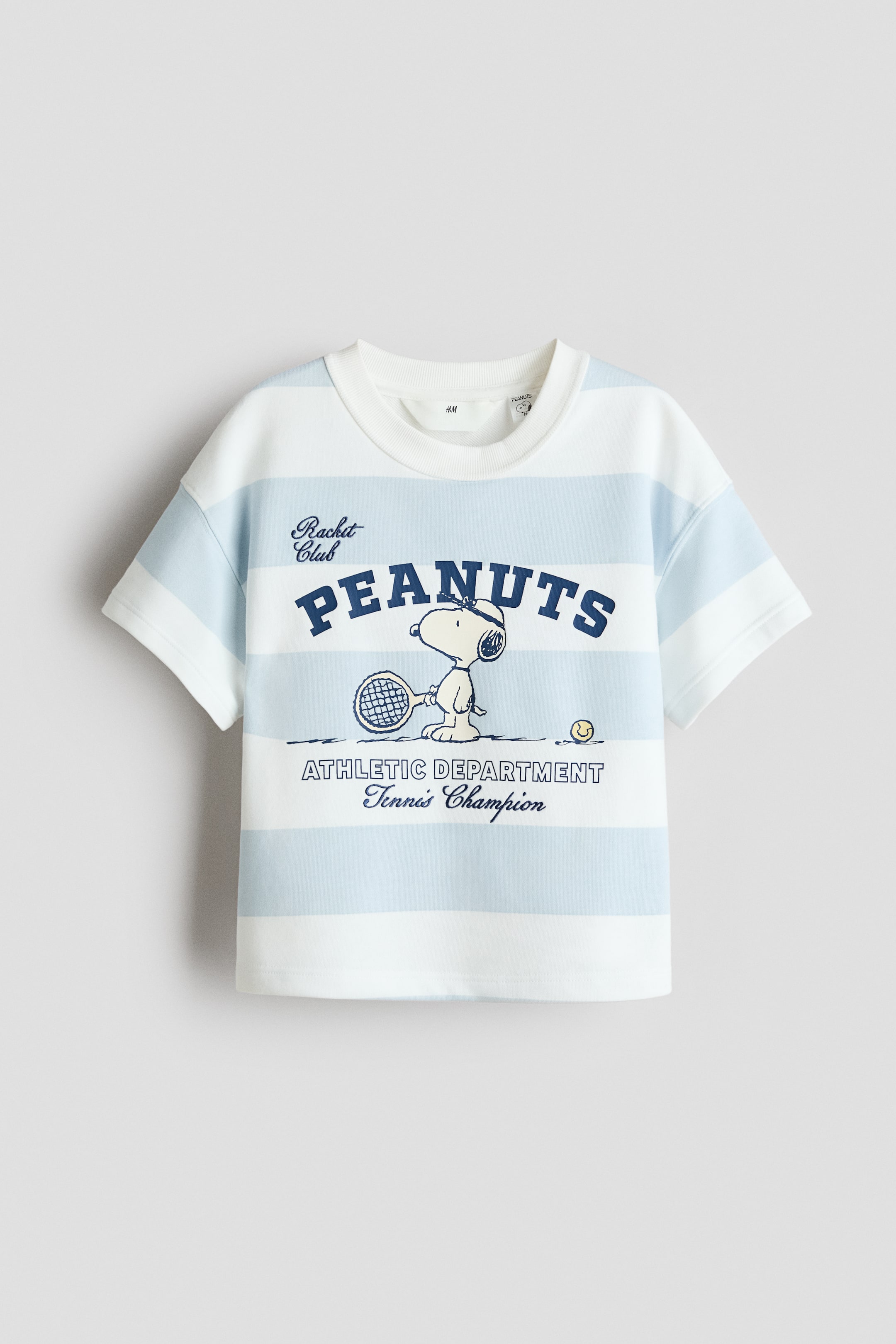 View larger image: 一件宽松版型的T恤，采用印花轻质卫衣面料，展示其正面视图，特色是白色和浅蓝色的横条纹。设计上配有圆形罗纹饰边领口、落肩、短袖，以及前面有深蓝色的史努比打网球图案和文字。
