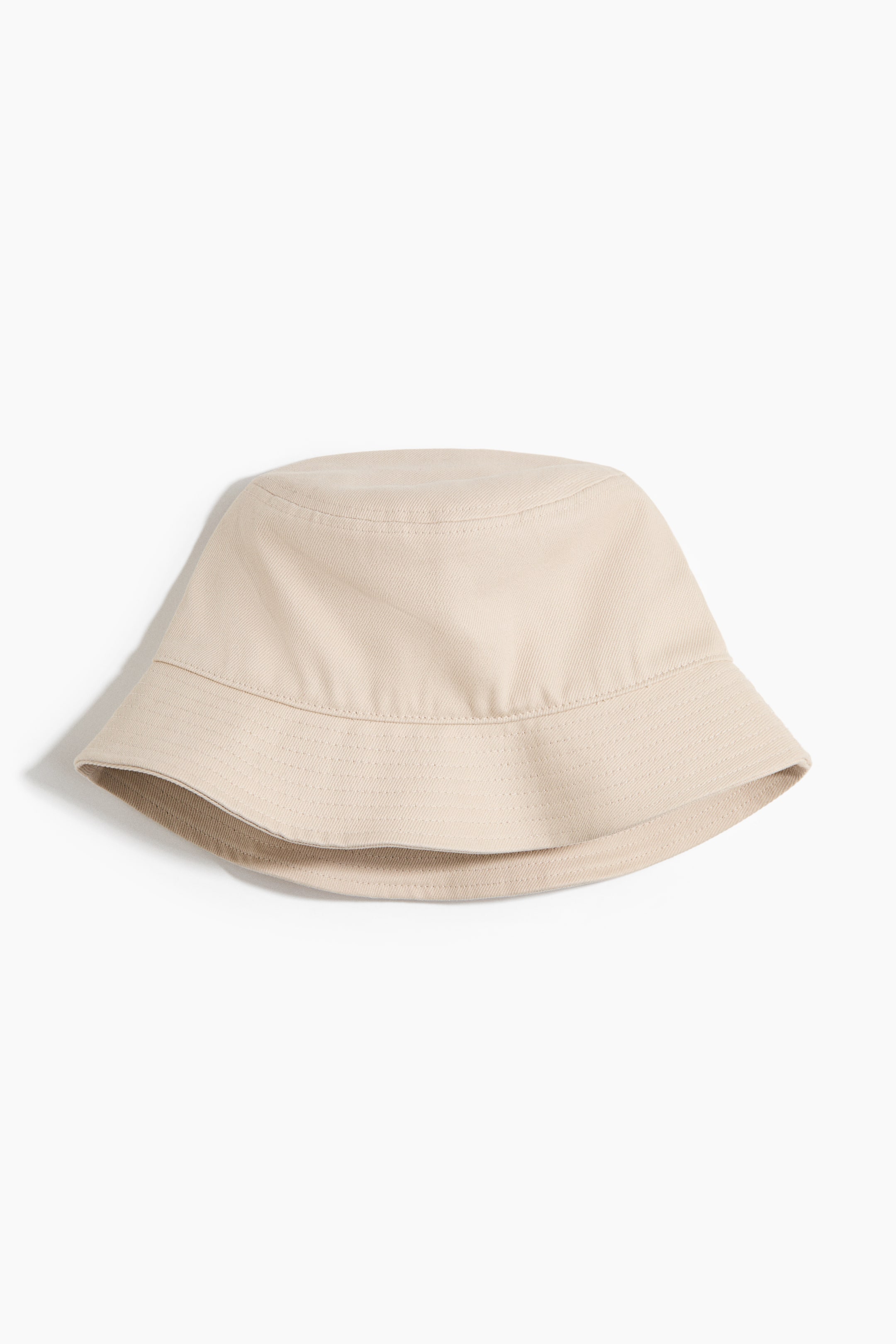 Ver imagen más grande: Se presenta un sombrero de cubo beige de FRENTE, con una corona redondeada y suave, y un ala ancha inclinada hacia abajo con costuras concéntricas visibles.