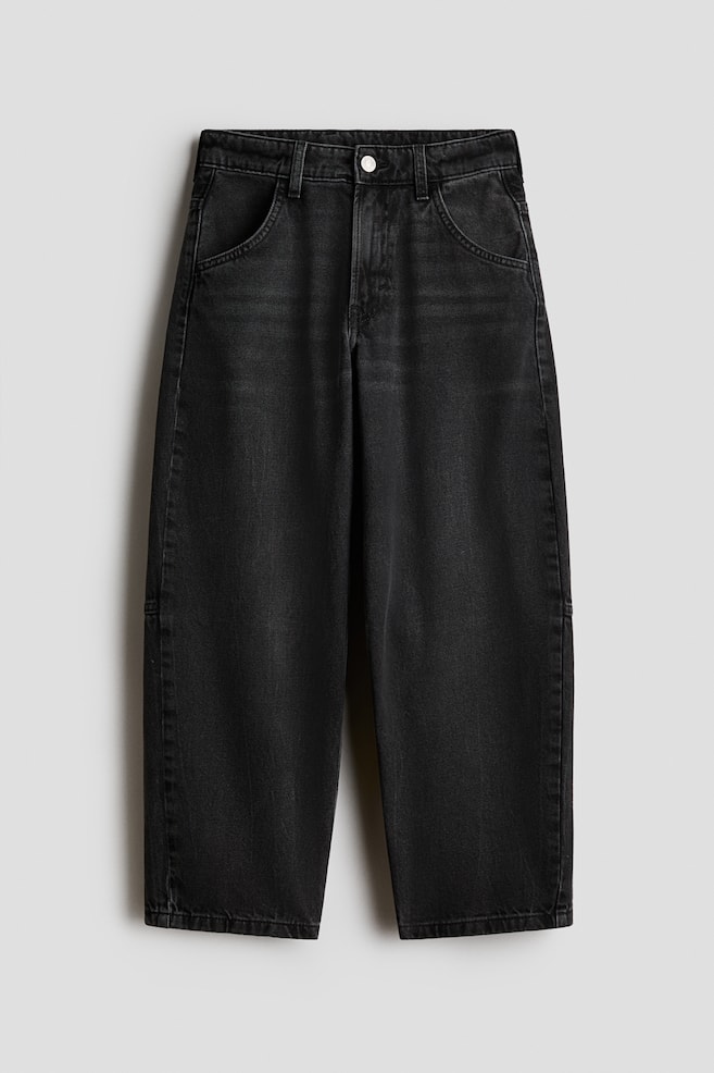 Deze vervaagde zwarte denim jeans zijn van voren te zien en hebben een wijde pijp met een licht toelopende silhouet. Ze zijn voorzien van afgeronde steekzakken, riemlussen en een enkele zilverkleurige knoopsluiting aan de tailleband. - 1