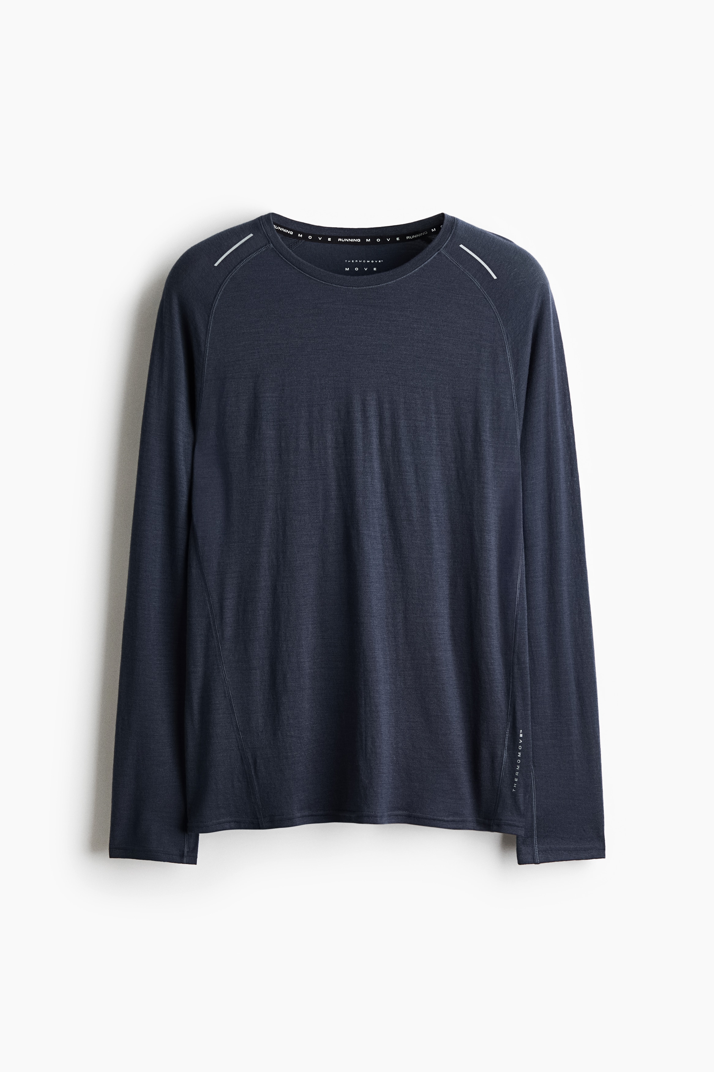 A dark blue-grey long-sleeve athletic shirt is shown from the front, featuring a crew neck and raglan sleeves with small reflective diagonal stripes on the shoulders. The lightweight garment displays clean, straight hems and subtle vertical seam detailing along the sides.
