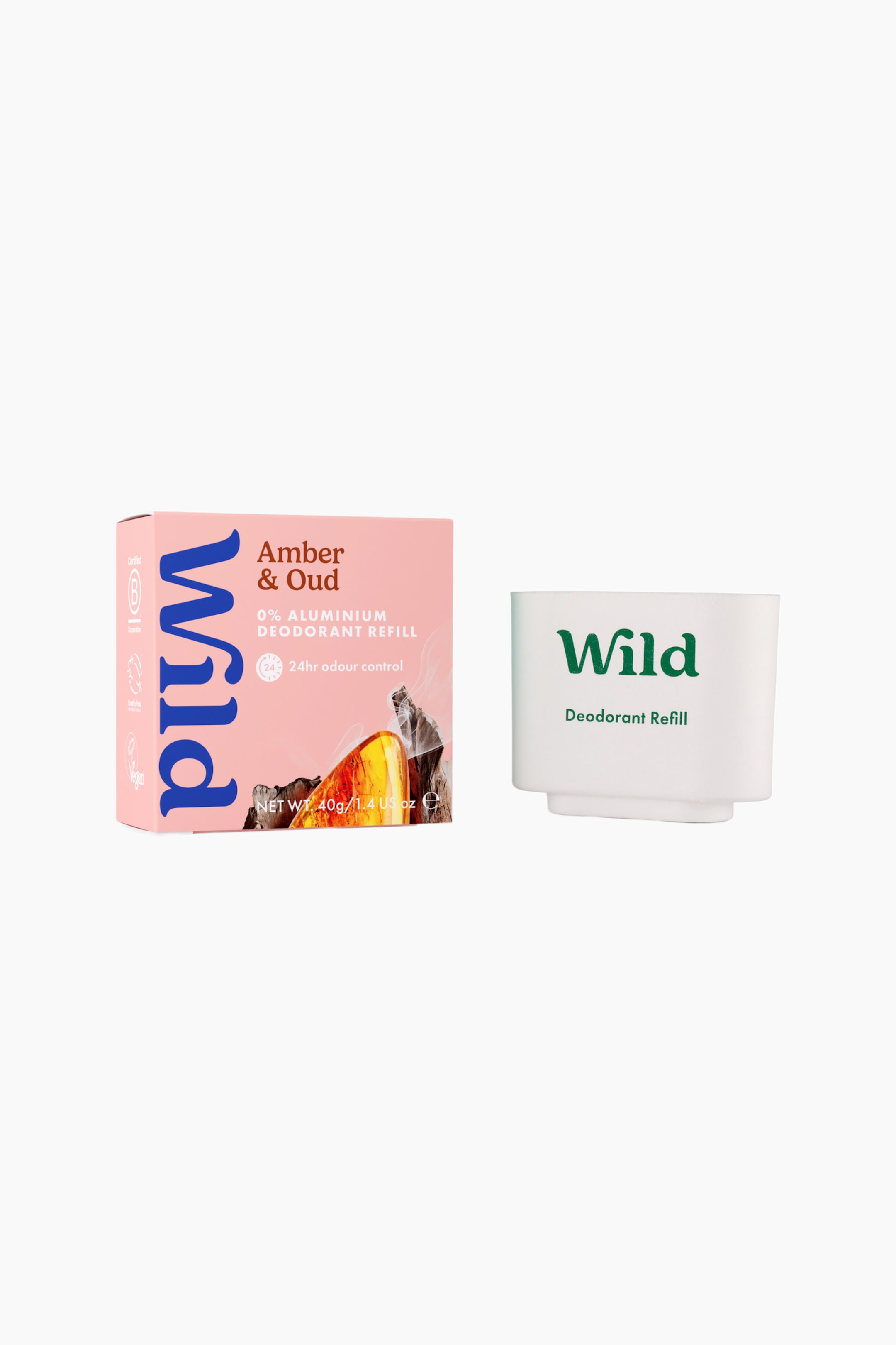 Se større billede: En deodorant refill vises med en pink papkasse til venstre og en hvid, formstøbt papirmassepatron til højre. Den pink kasse viser brandnavnet "Wild" i stor blå lodret tekst sammen med "Amber & Oud"-detaljer, mens den hvide patron står oprejst og viser det grønne "Wild"-logo og teksten "Deodorant Refill" på forsiden.