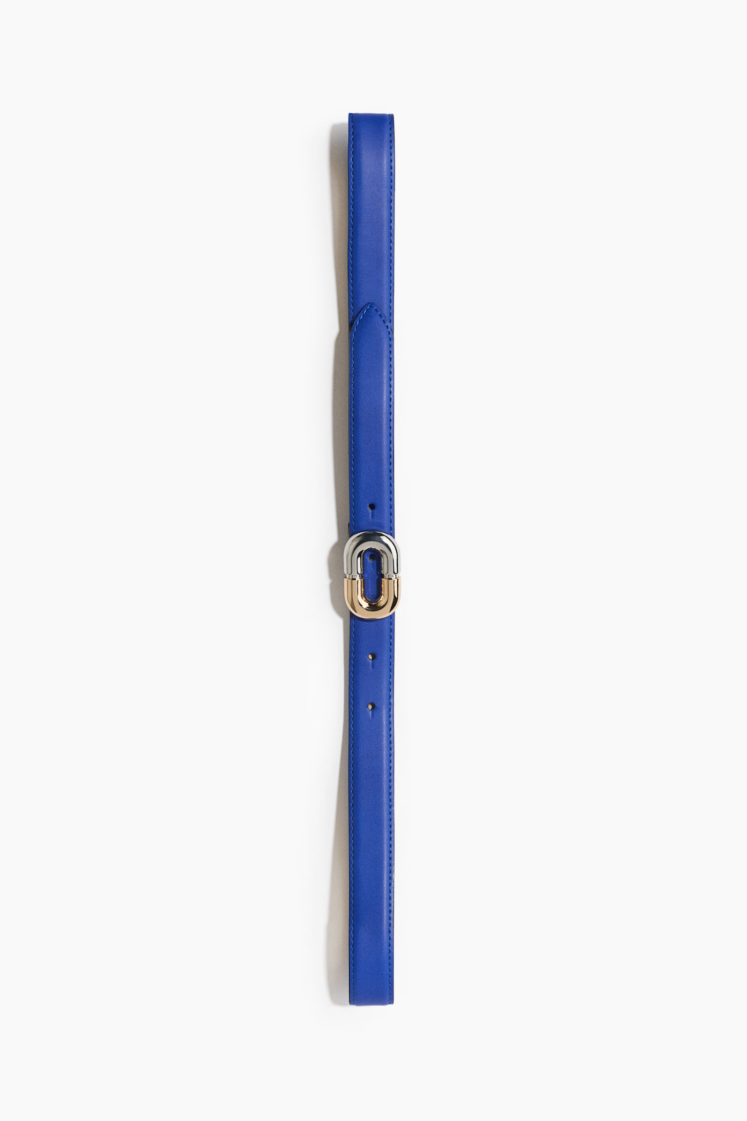A vibrant blue leather belt is lying vertically, facing forwards, showcasing its smooth texture and tonal edge stitching. It features a distinctive rounded, two-tone metal buckle in the centre, with interlocking silver-toned and gold-toned finishes.