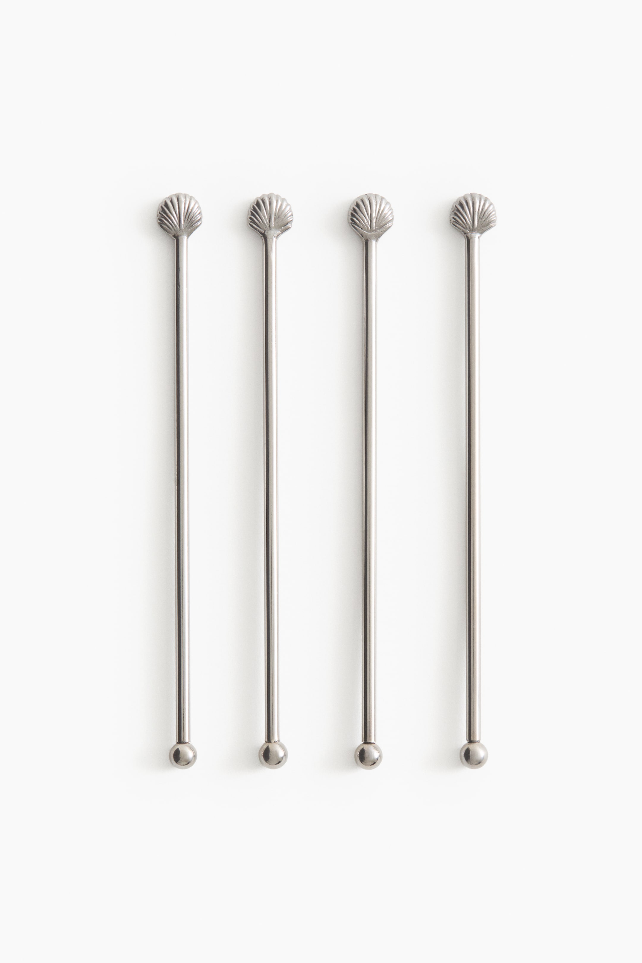 Grotere afbeelding bekijken: Vier zilverkleurige metalen cocktailroerstaafjes liggen verticaal op een rij, elk met een decoratieve schelpvormige top en een kleine bolvormige knop aan de onderkant.