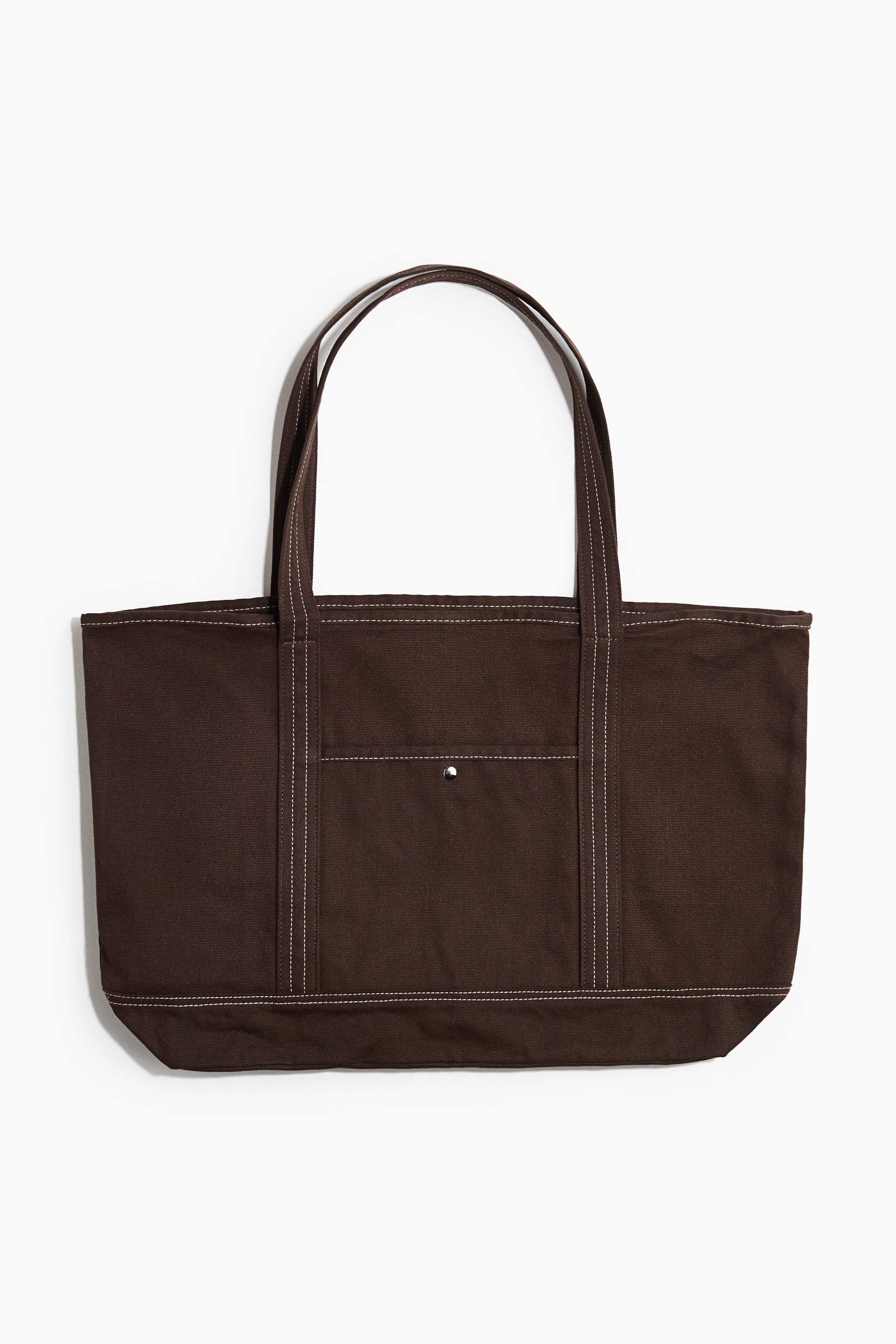 Visualizza immagine più grande: Una borsa tote in cotone marrone scuro è mostrata frontalmente, con due manici superiori e una tasca frontale esterna con chiusura a pressione argentata. Le cuciture bianche a contrasto rifiniscono le cuciture, i manici e i bordi della tasca.