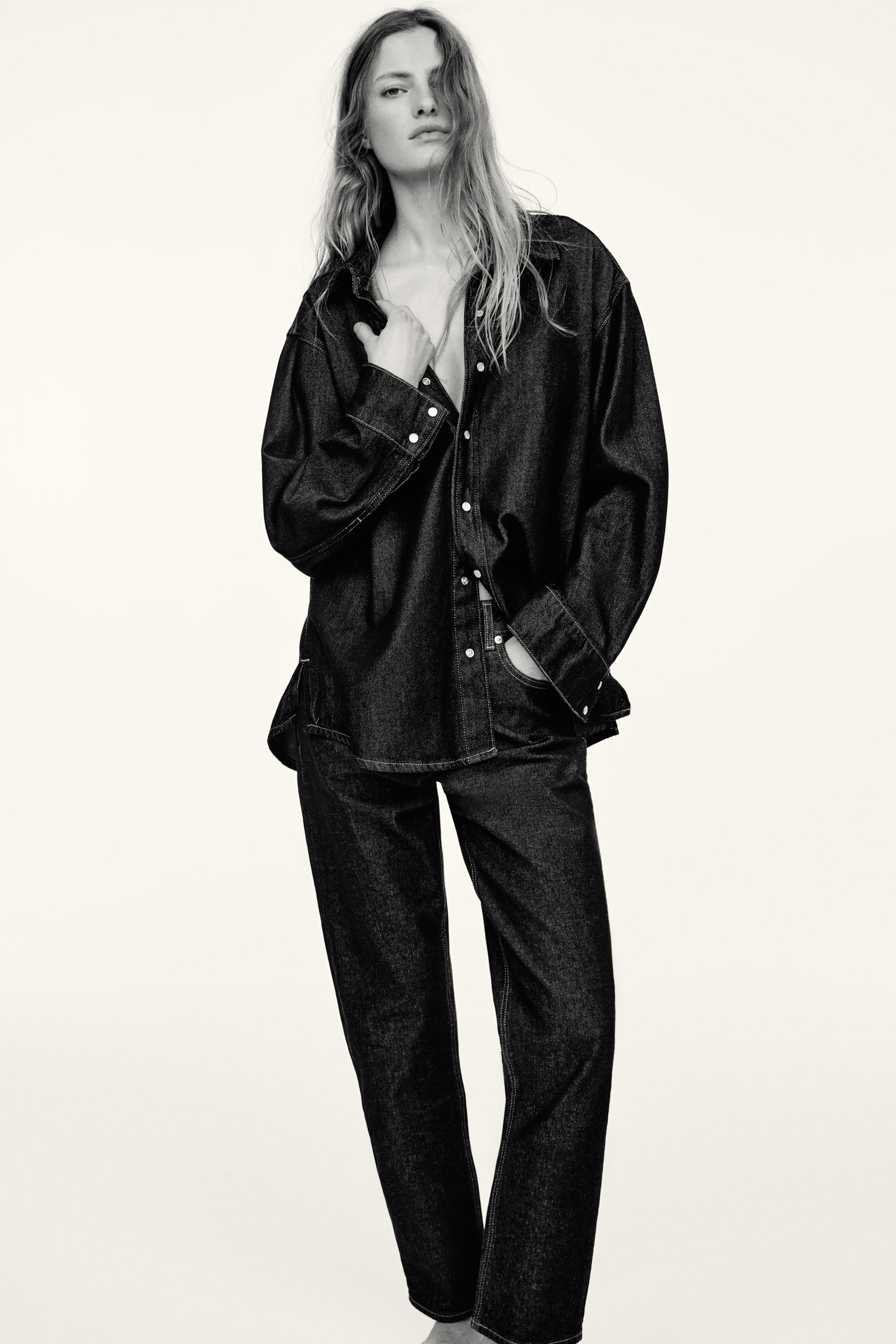 View larger image: "Satu kemeja denim berwarna gelap dan seluar jeans potongan lurus yang sepadan sedang dipersembahkan dari sudut hadapan. Kedua-dua kemeja bersaiz besar, digayakan tidak berbutang untuk menunjukkan butang berwarna cerah dan lengan panjang, serta seluar jeans potongan lurus yang sepadan menampilkan jahitan kontras putih yang menonjol."