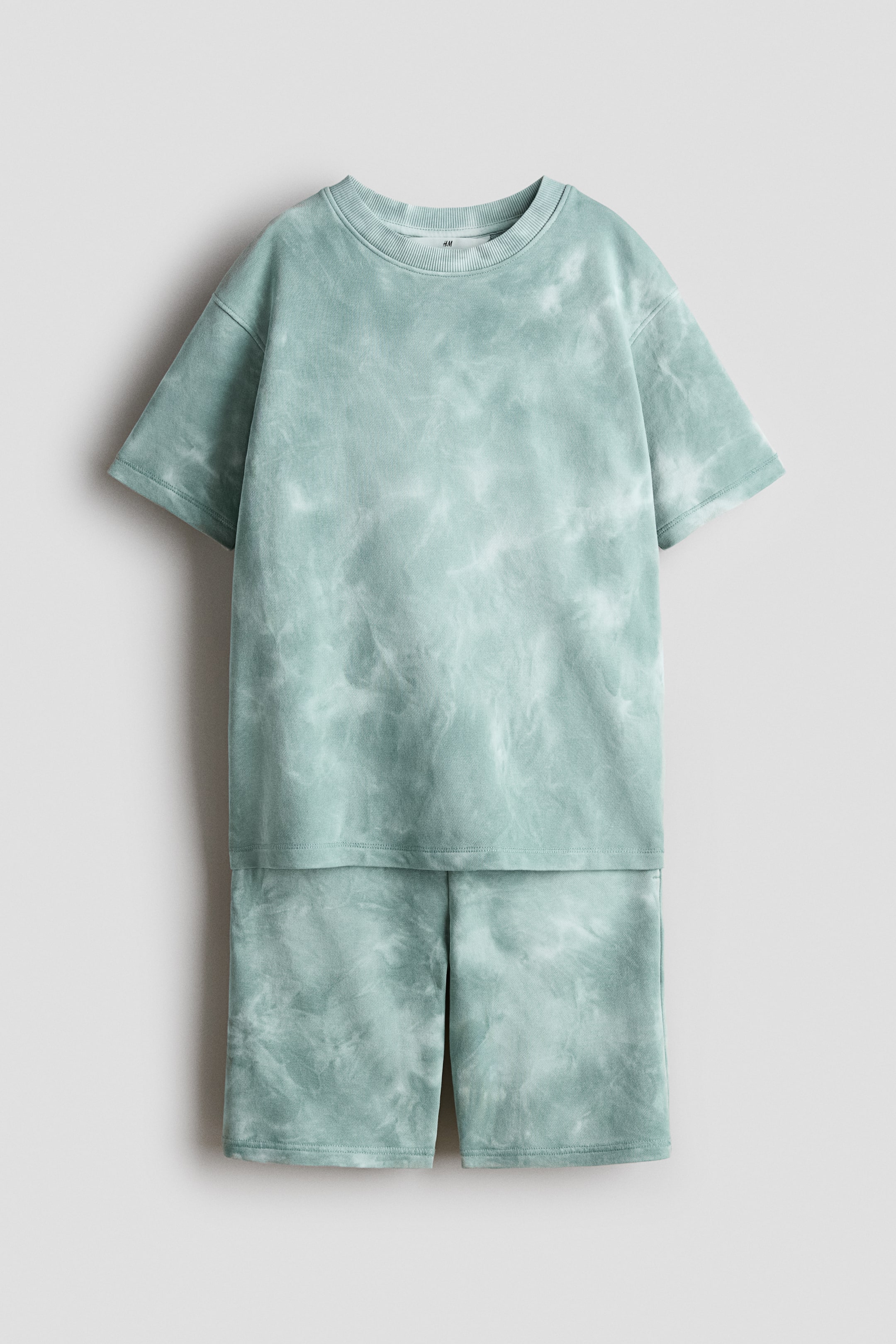 View larger image: A front-facing two-piece clothing set is featuring a greenish-blue and white tie-dye pattern. The short-sleeved t-shirt is designed with a ribbed crew neck and a straight hem, while the matching shorts are presenting a straight hem and reaching approximately mid-thigh.