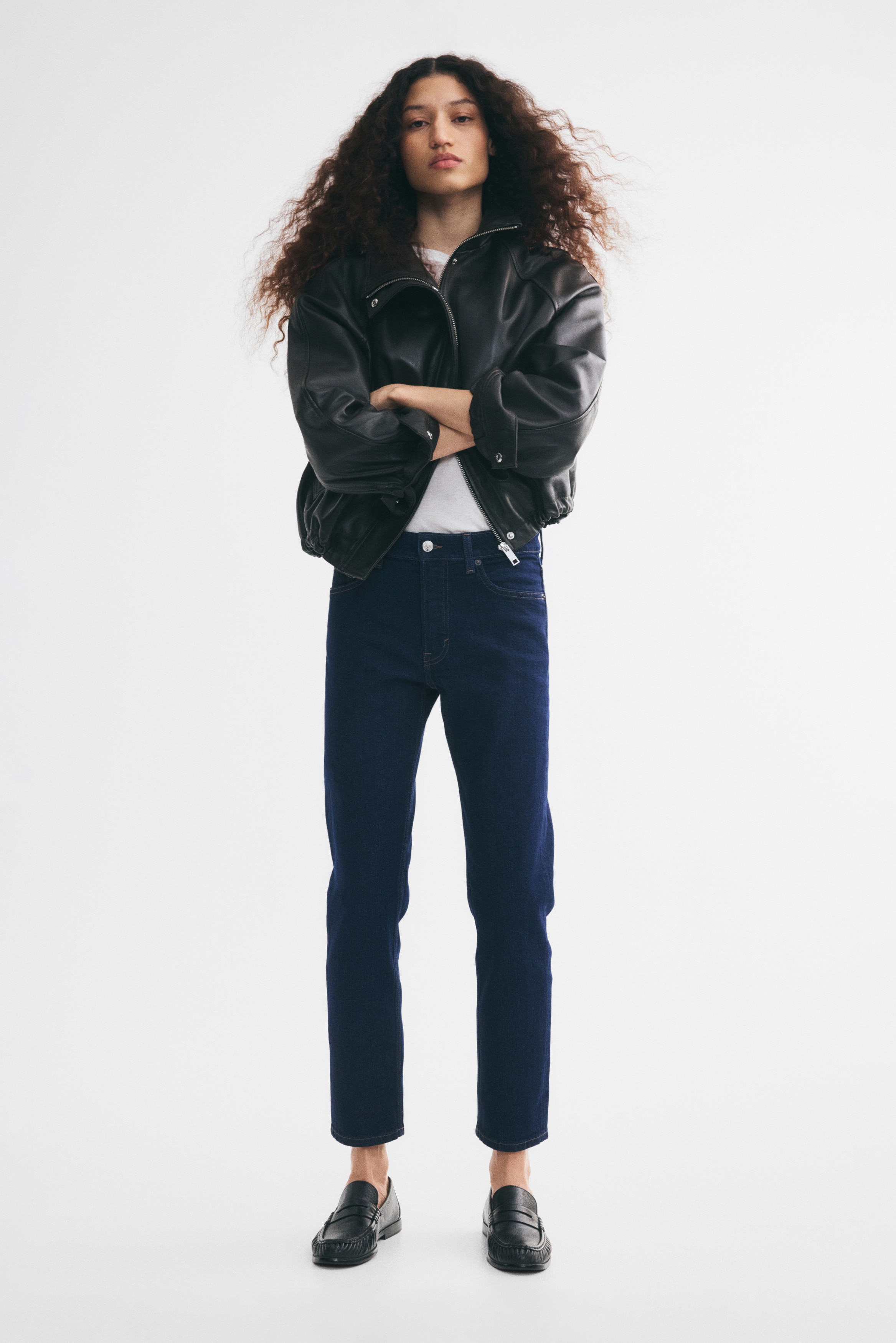 Dark blue denim jeans are showcasing a front view, featuring a straight-leg cut, two front scoop pockets with metal rivets, a coin pocket, a button fly fastening, and contrast light brown stitching.
