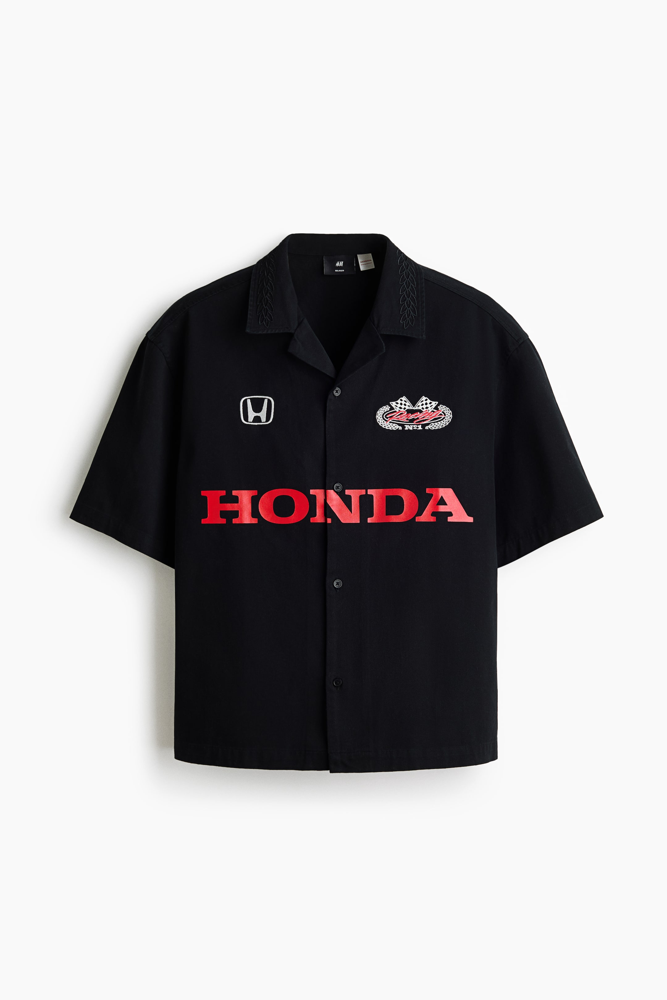 View larger image: A black short-sleeved shirt features an open revere collar with embroidered detailing. The front of the shirt displays a white Honda logo on the upper left, an embroidered racing patch on the upper right, and large red 'HONDA' text across the chest.