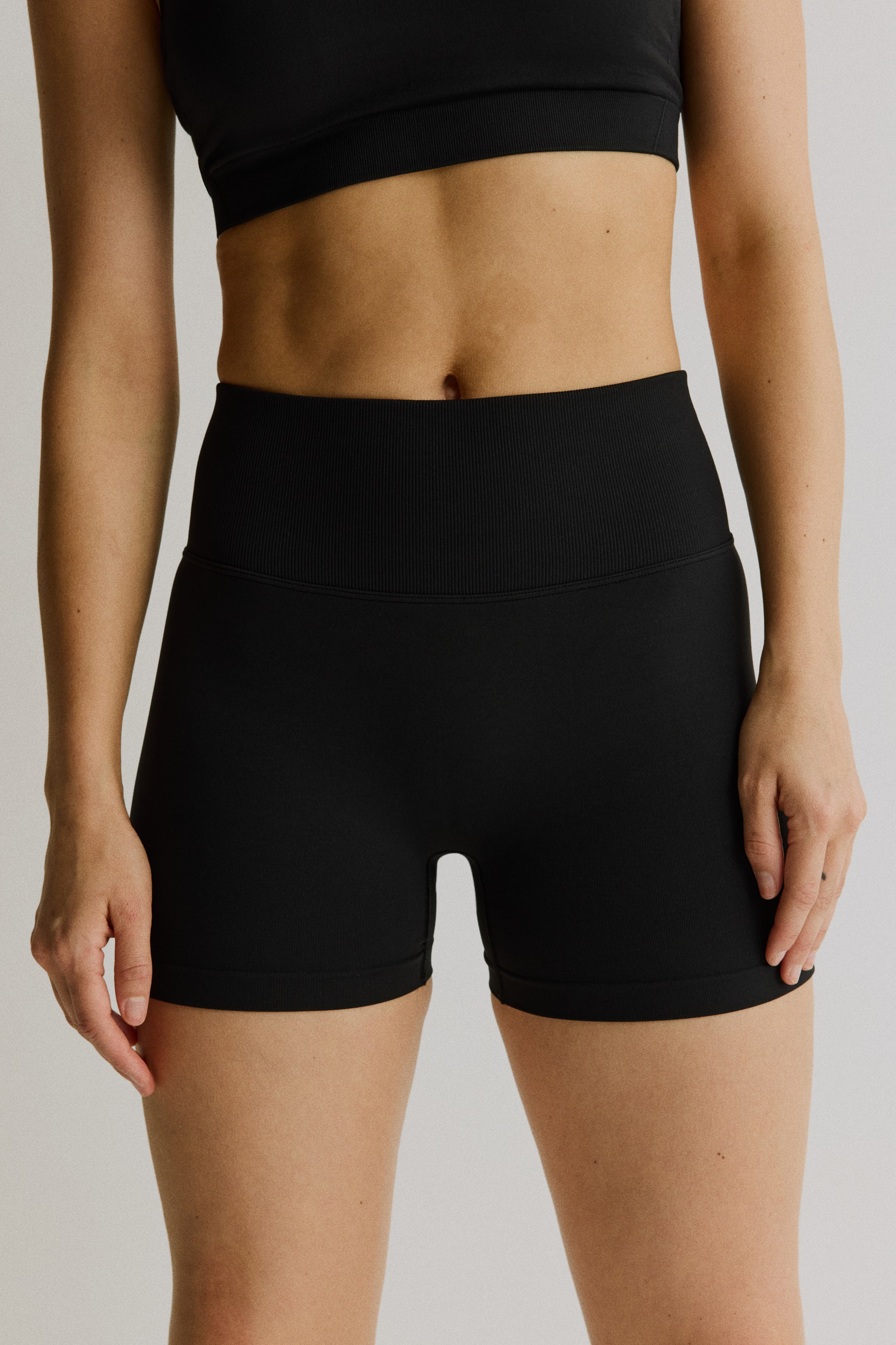 Vis større bilde: Svarte sømløse hotpants, med en ribbestrikket høy midje, bæres av modellen.