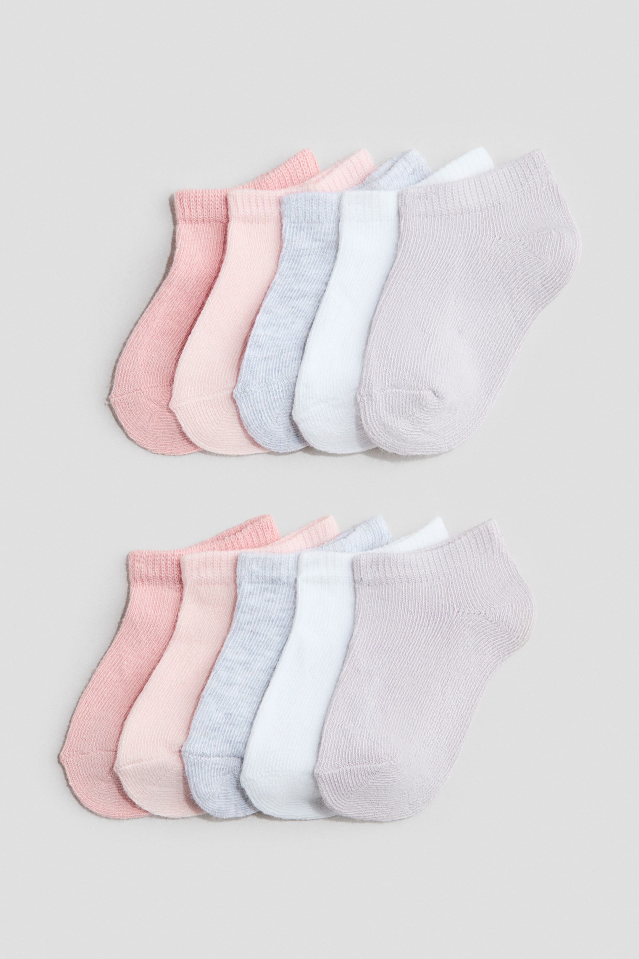 Grösseres Bild ansehen: Zehn schaftlose Socken liegen flach, in zwei Reihen angeordnet. Jede Reihe zeigt fünf Socken in Hellrosa, Hellpfirsich, Hellblau meliert, Weiss und Hellgrau, alle mit einer feinen Strickstruktur und gerippten Bündchen.