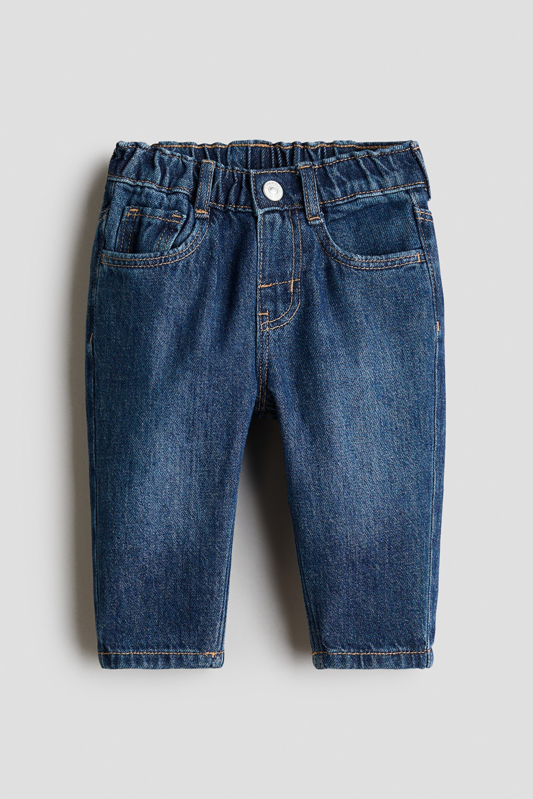 View larger image: These dark wash 5-pocket jeans in soft cotton denim feature tapered legs and an elasticated waistband, facing forward. They showcase a faux fly with a single silver press-stud, front pockets, and a coin pocket.