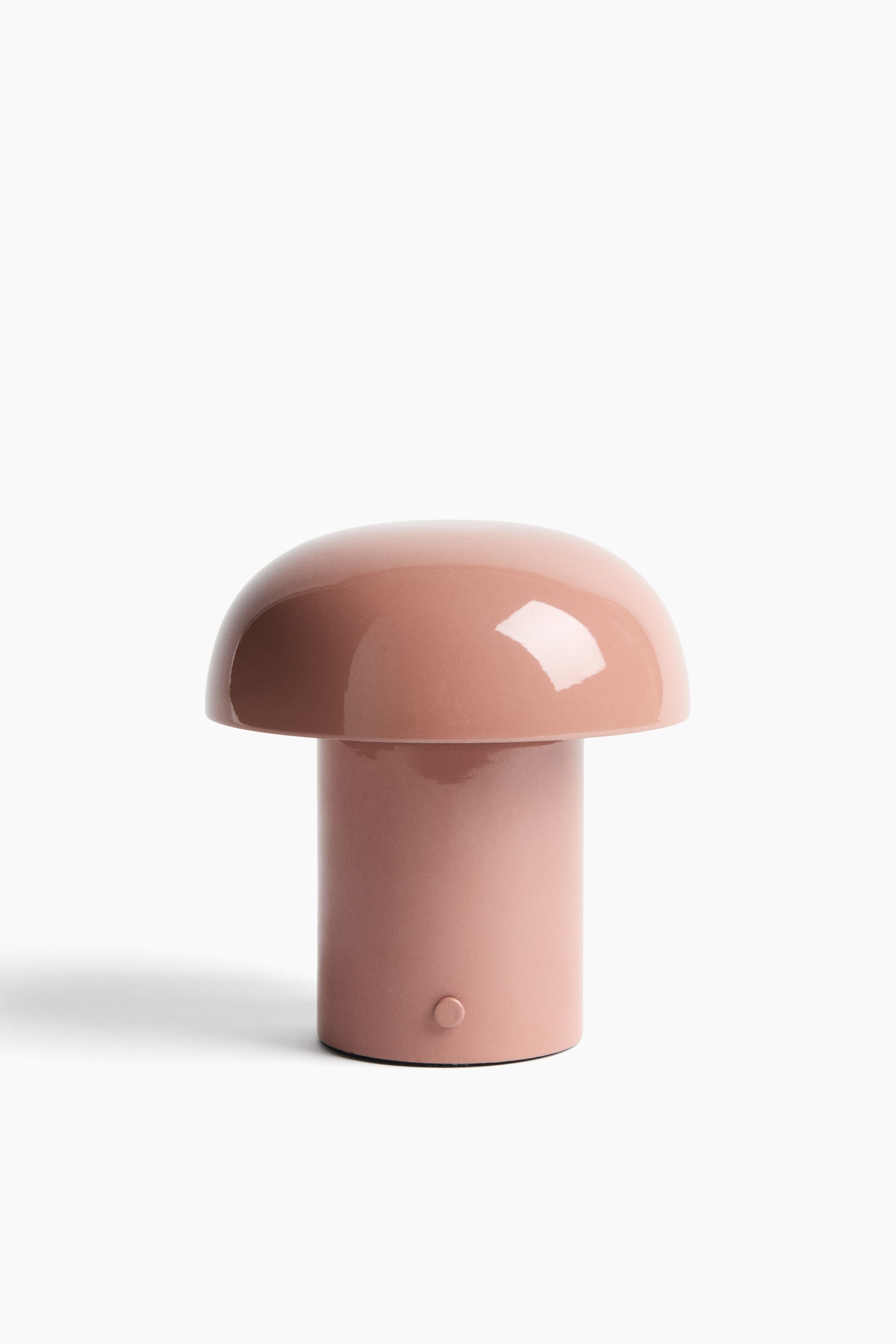 View larger image: The rechargeable table lamp features a rounded, mushroom-inspired design in pinkish-brown metal. It is shown from the front, with a domed top resting on a cylindrical base that exhibits a small circular on/off switch near its bottom.