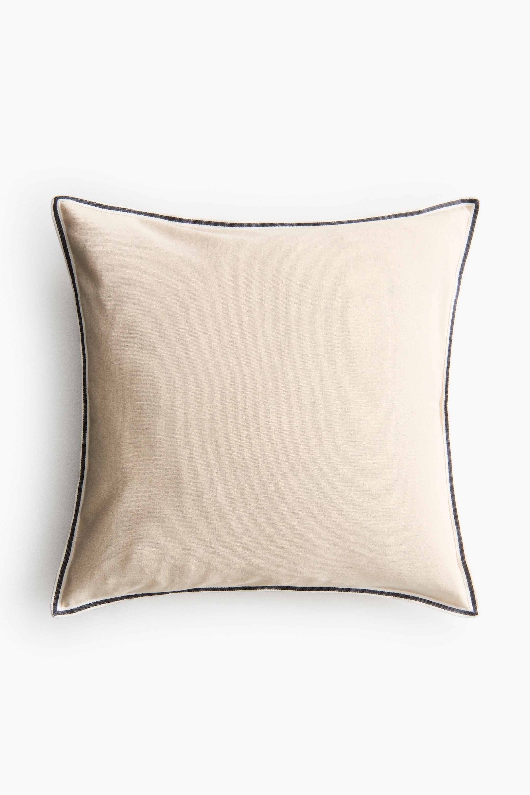 View larger image: A cushion is shown from the front, featuring a light beige fabric with dark blue piping outlining its rectangular shape.