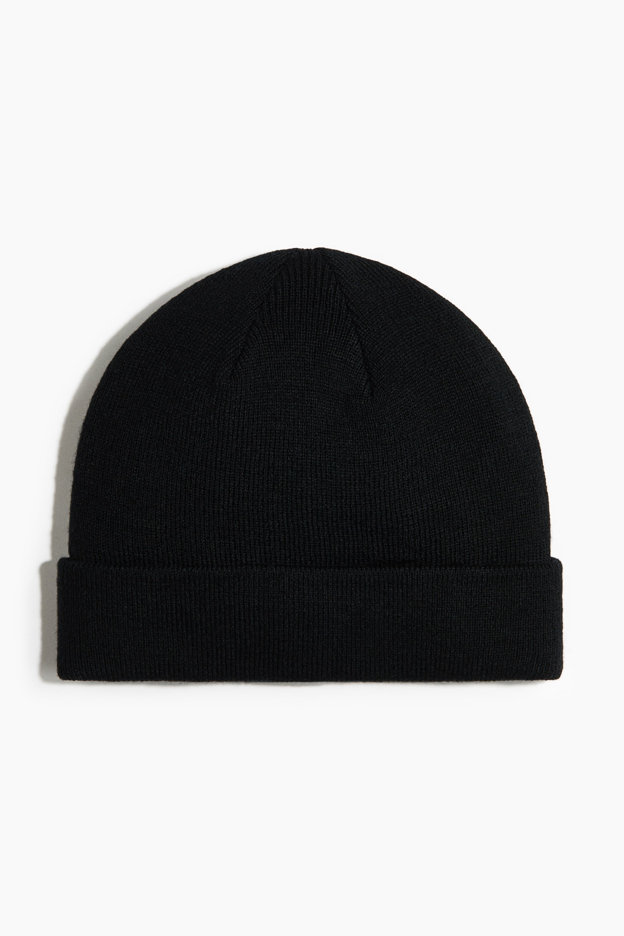 Grösseres Bild ansehen: Eine schwarze Beanie ist von vorne zu sehen, mit feiner Strickstruktur und umgeschlagenem geripptem Saum.