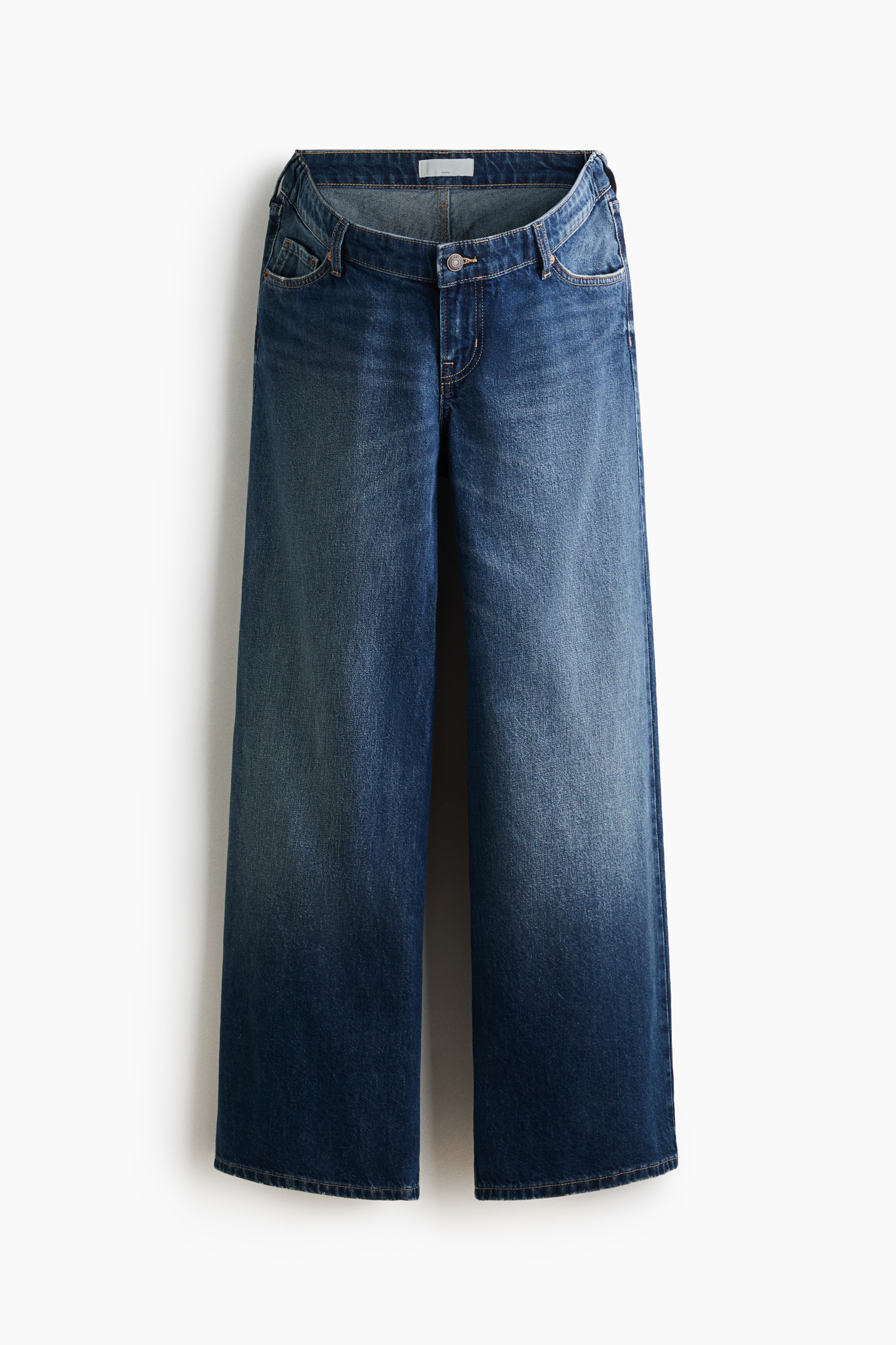 Blue wide-leg denim jeans featuring a low-rise waist and a faded blue wash are being worn by the model. The jeans are styled with a white tank top and an open, light grey zip-up hoodie.