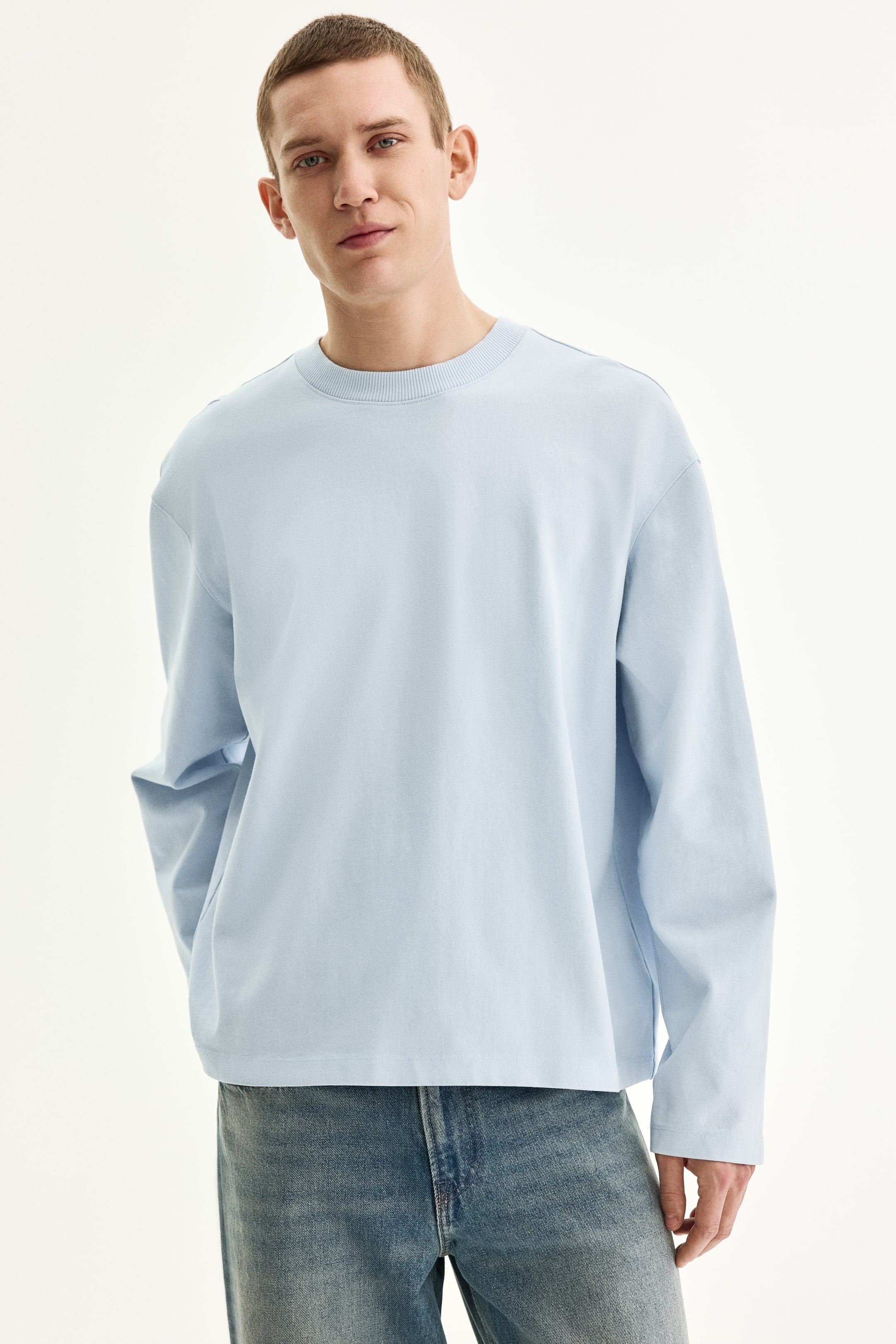 View larger image: A light blue crewneck sweatshirt features a ribbed collar, dropped shoulders, and long, loose sleeves, with a relaxed fit and a straight hem that falls to the hips.