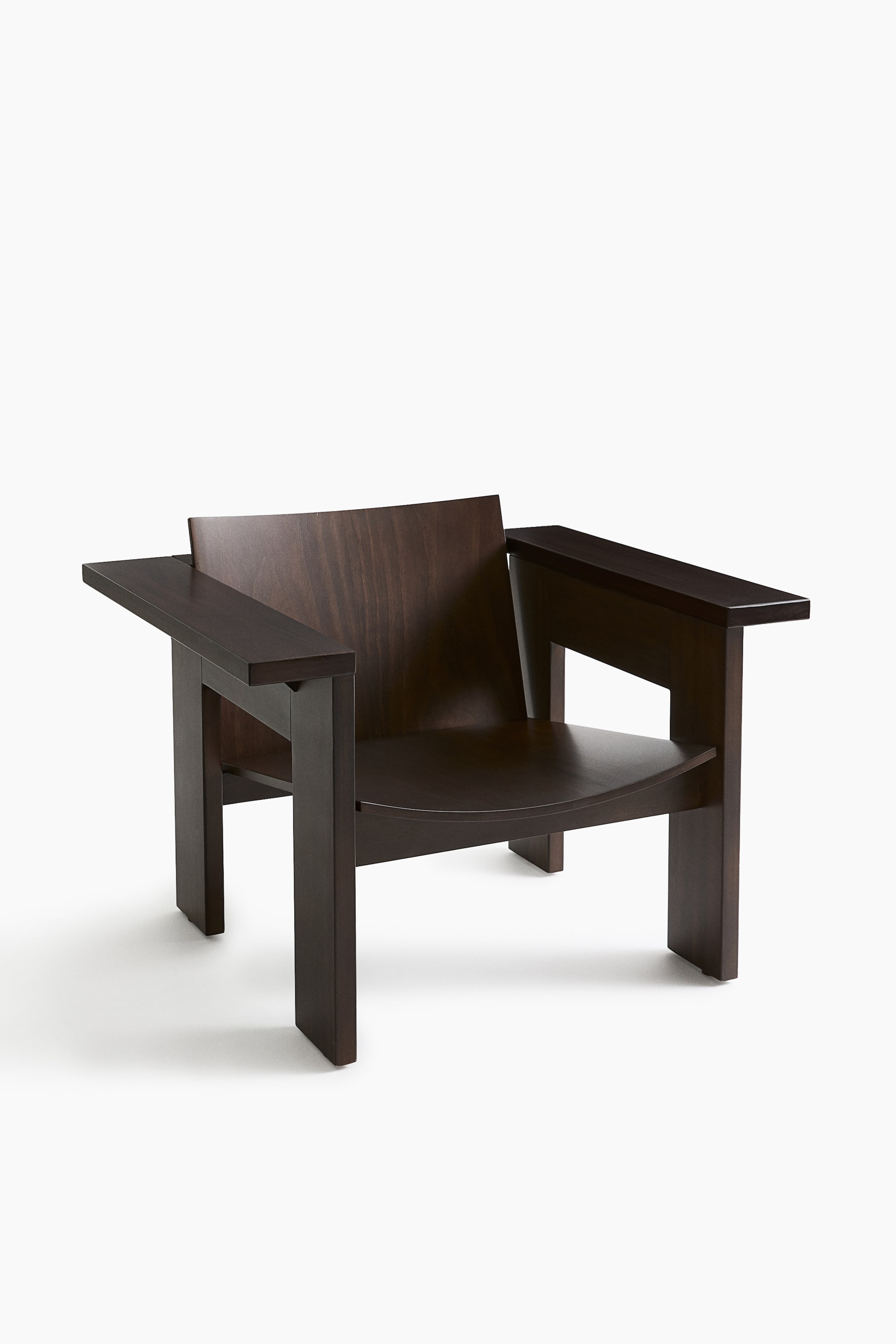 Agrandir l'image: Une chaise en bois brun foncé est légèrement orientée vers la droite, mettant en valeur son design géométrique. Elle présente un dossier plat légèrement incurvé, de larges accoudoirs plats et une assise incurvée en forme de cuvette, le tout en bois sombre avec un grain visible.