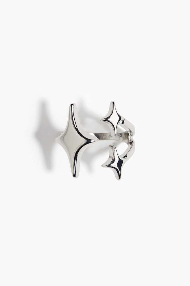 A polished metal ring is showcasing its open design as FRONT. It is featuring three-dimensional star-shaped elements, with one large star on one end and two smaller stars on the opposite end of the open band. - 1
