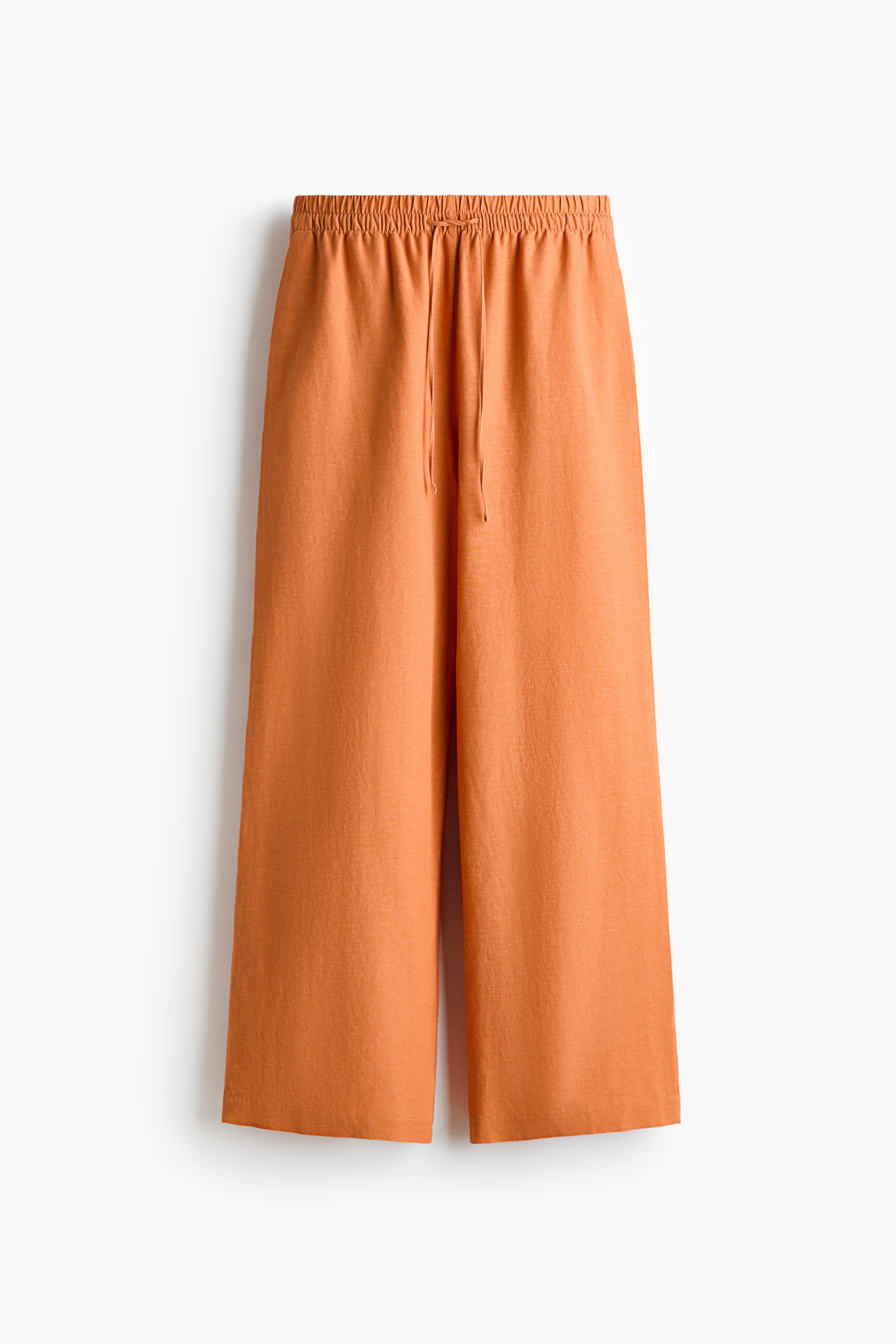 View larger image: Orange loose-fit trousers are showcased front-facing, featuring an elasticated, drawstring waist, discreet side pockets, and wide legs, all crafted from an airy linen and viscose weave.