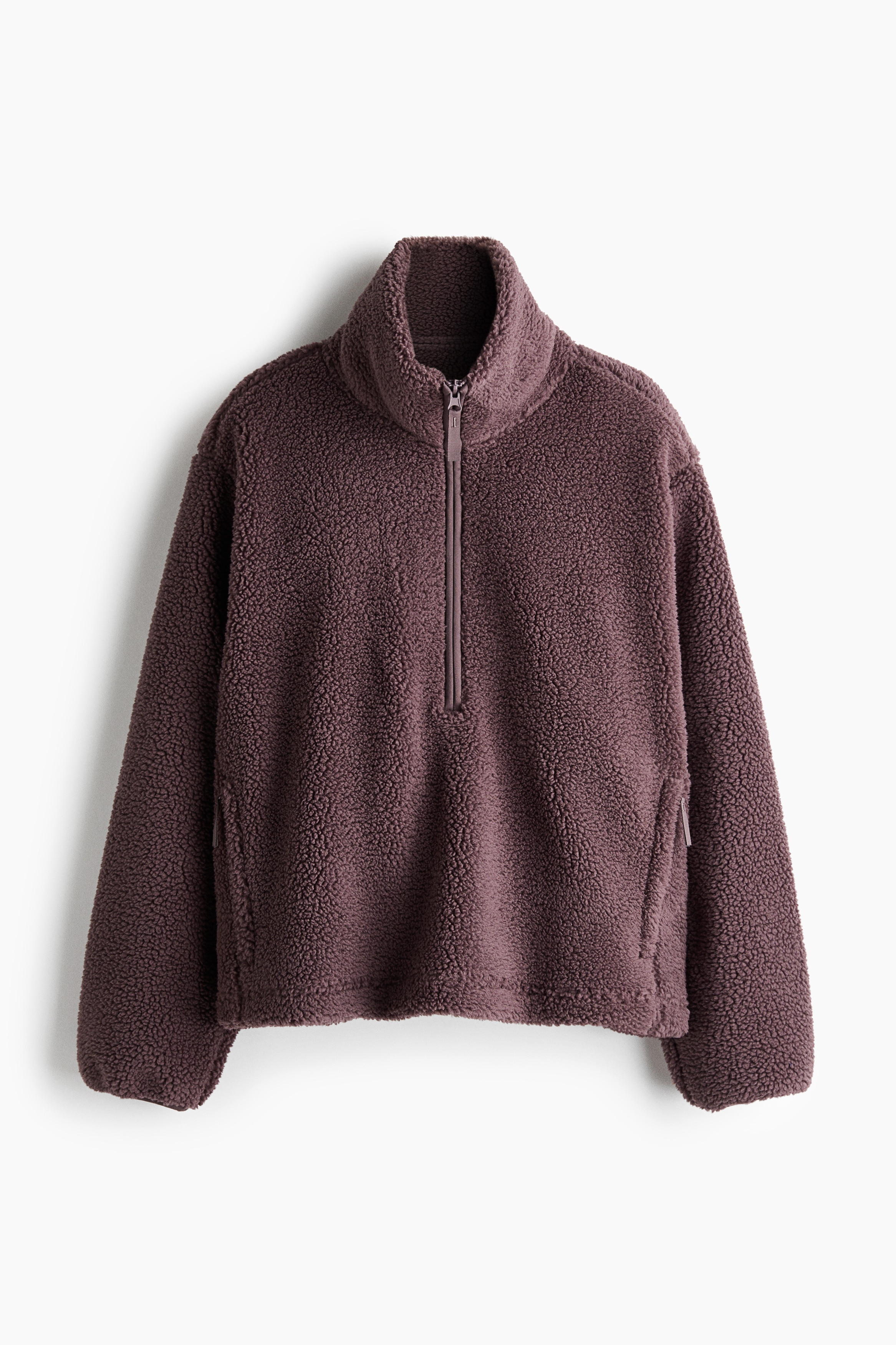 A dark plum-coloured, high-pile fleece jacket with a high funnel collar and a relaxed fit is worn by the model. The jacket is styled with black leggings and cream-coloured faux fur boots.