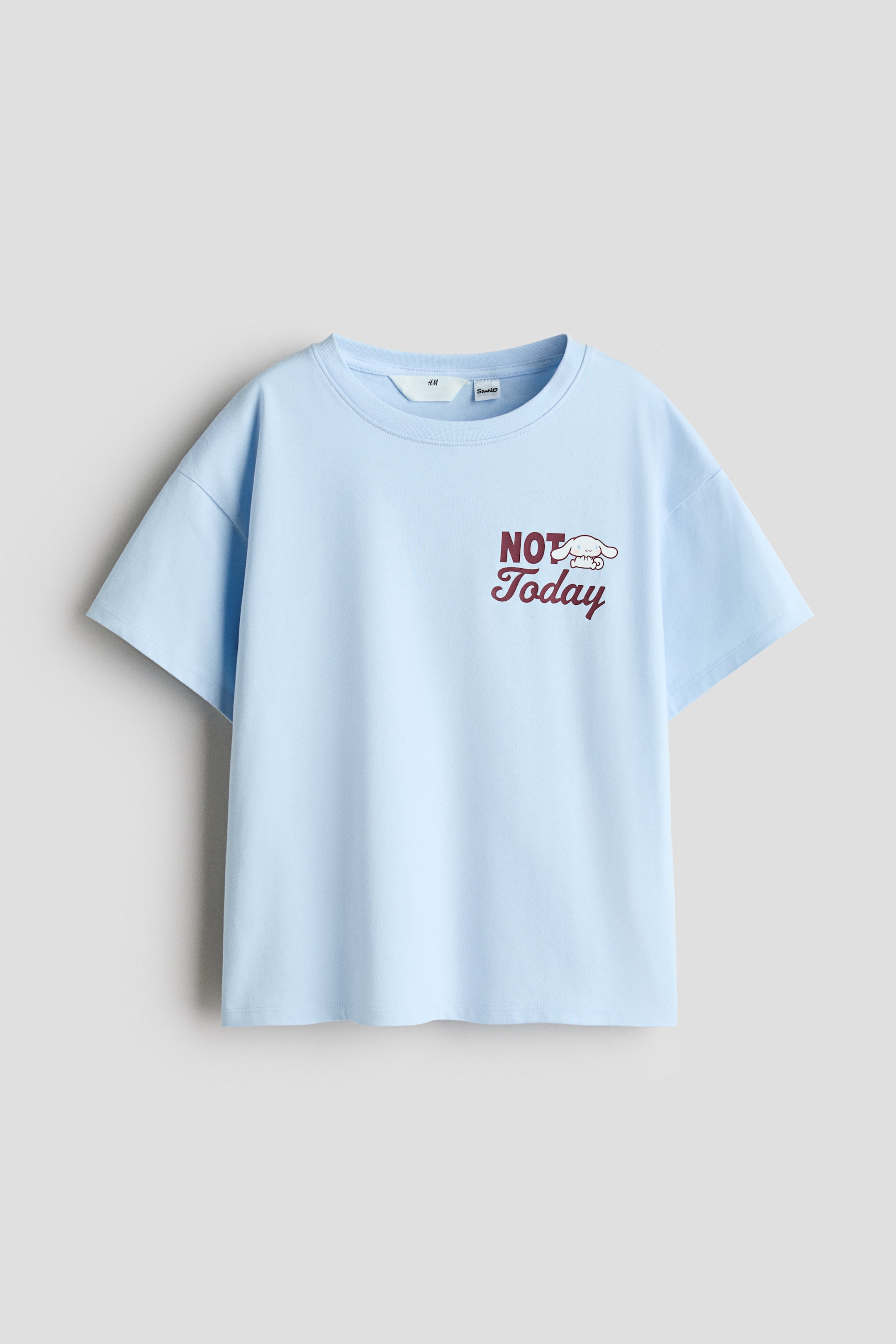 Se større billede: En lyseblå t-shirt med en rund, ribkantet halsudskæring, blødt faldende skuldre og en frontgrafik med mørkerød "NOT Today" tekst og en hvid tegneseriefigur.