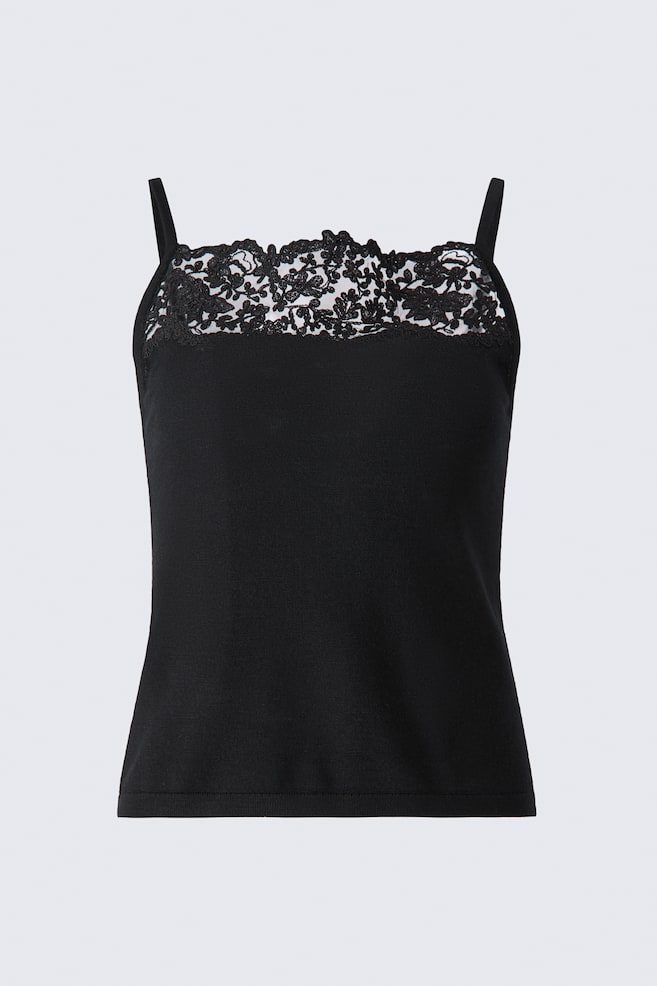 A black knitted camisole top is shown from the front, featuring narrow shoulder straps and a square neckline. Intricate, irregular-edged black floral lace with subtle tonal sequins details the front neckline, while a fine ribbed band finishes the straight hem. - 1