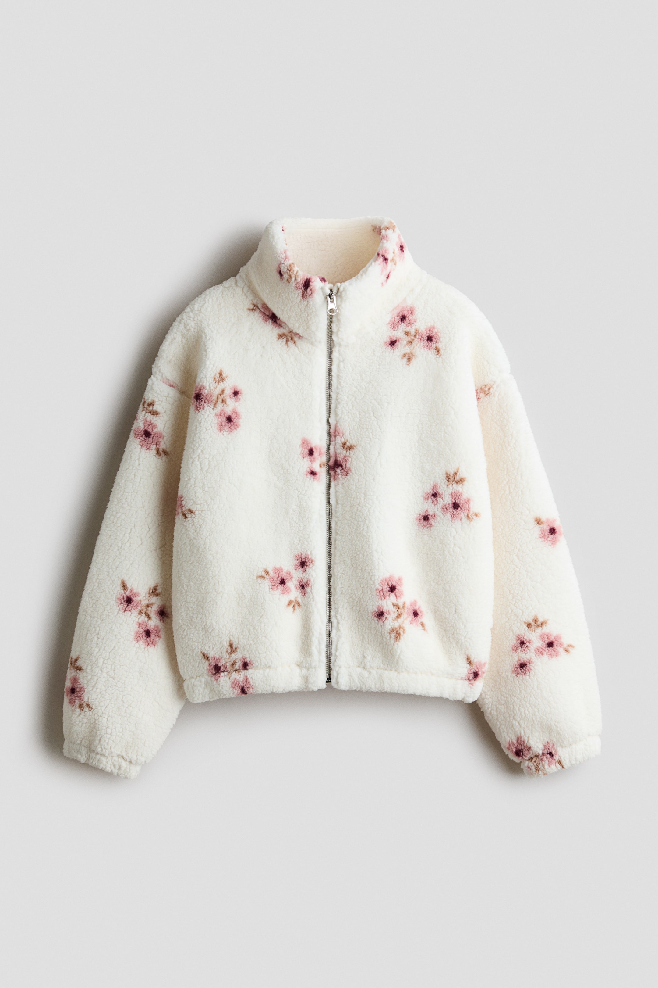 View larger image: A front view of a loose-fitting teddy jacket in off-white featuring a pink floral pattern, a high stand collar, and a full-length front zipper. The jacket is displayed with dropped shoulders, long sleeves with elasticized cuffs, and an elasticized hem.