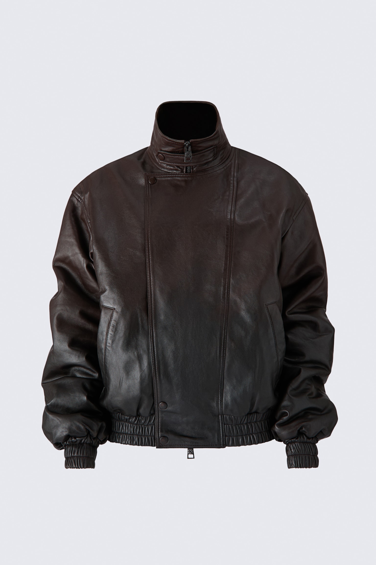 A front-facing dark brown leather jacket featuring a high funnel collar with a front zipper and an overlapping asymmetrical panel with snap-button closures. The jacket has relaxed, slouchy sleeves with gathered elasticized cuffs and a matching elasticized hemline.