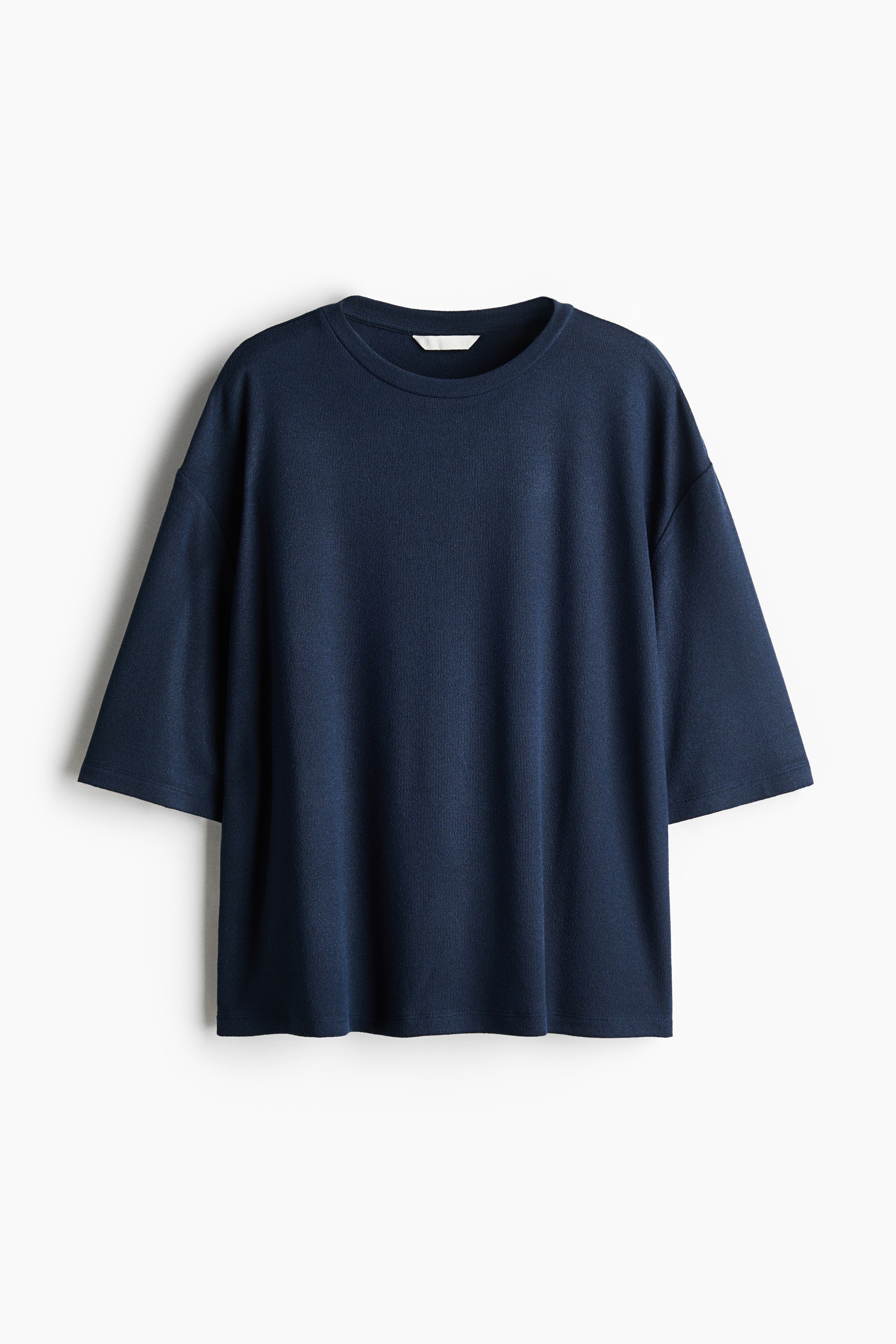 A navy blue crewneck T-shirt with relaxed, elbow-length sleeves is paired with wide-leg, light-wash blue jeans in a front-facing view. The relaxed-fit jeans feature a faded wash, a low-to-mid rise waist, and a classic five-pocket design.